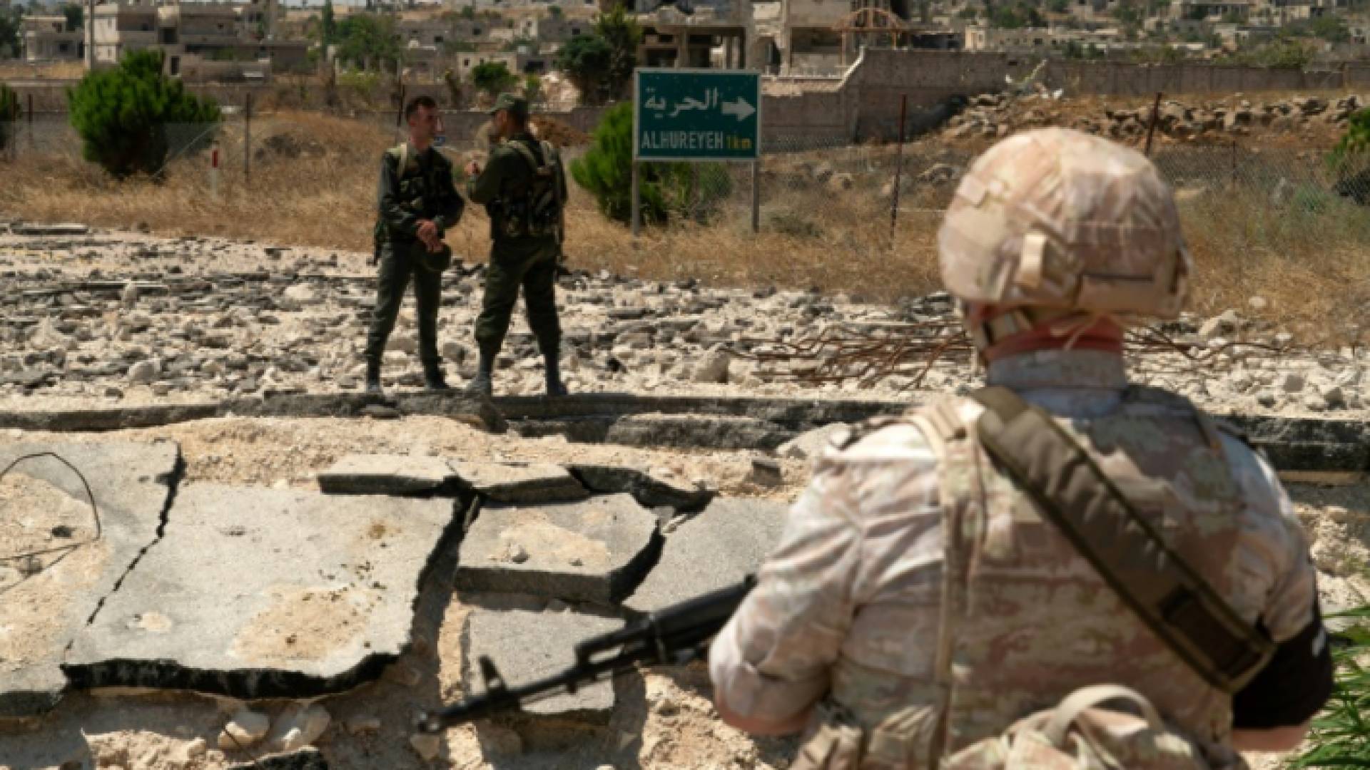 جندي روسي يقف قبالة جنديين سوريين قرب قرية الحميدية في هضبة الجولان