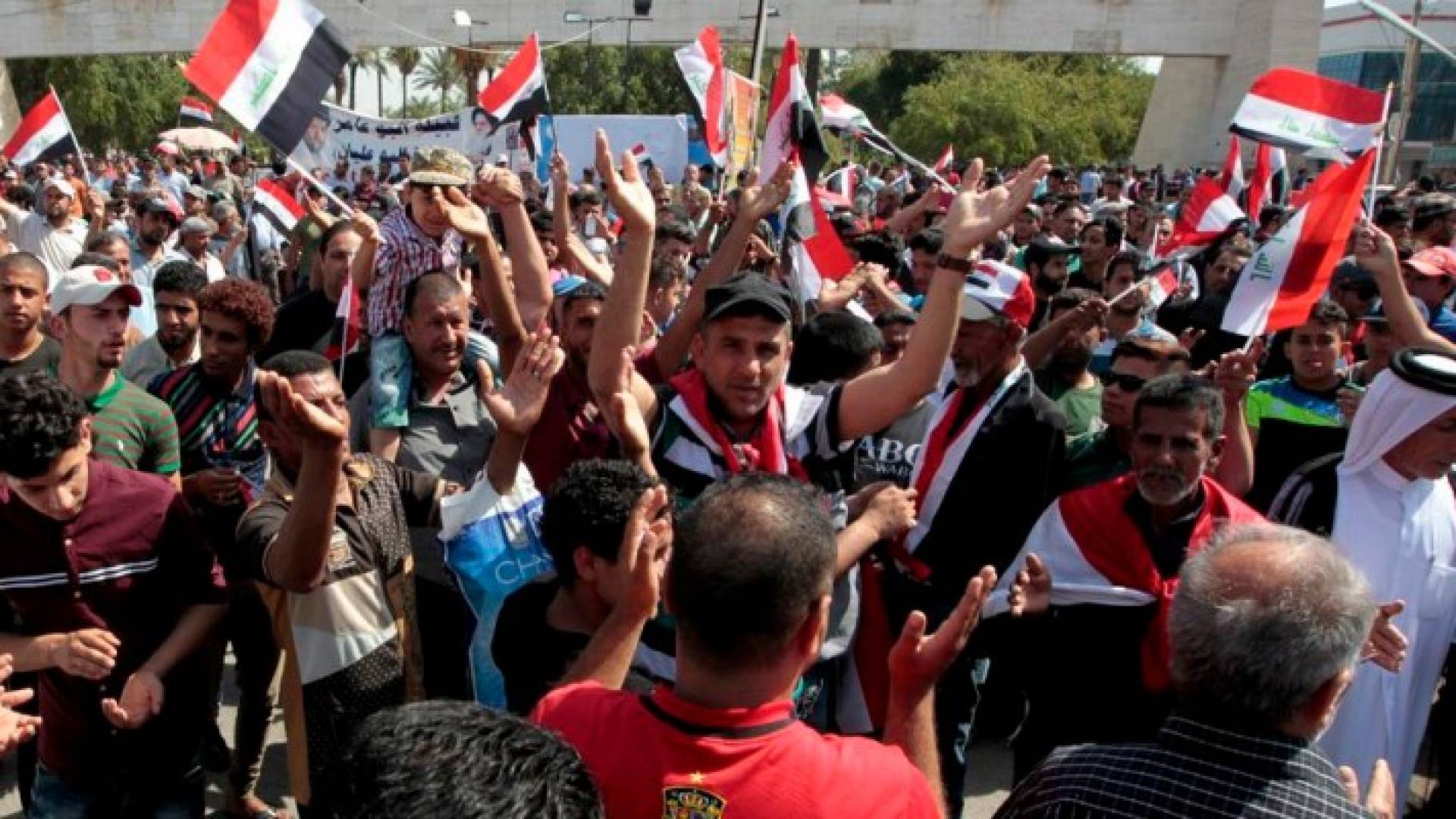  المحتشدون وهم يلوحون بأعلام العراق