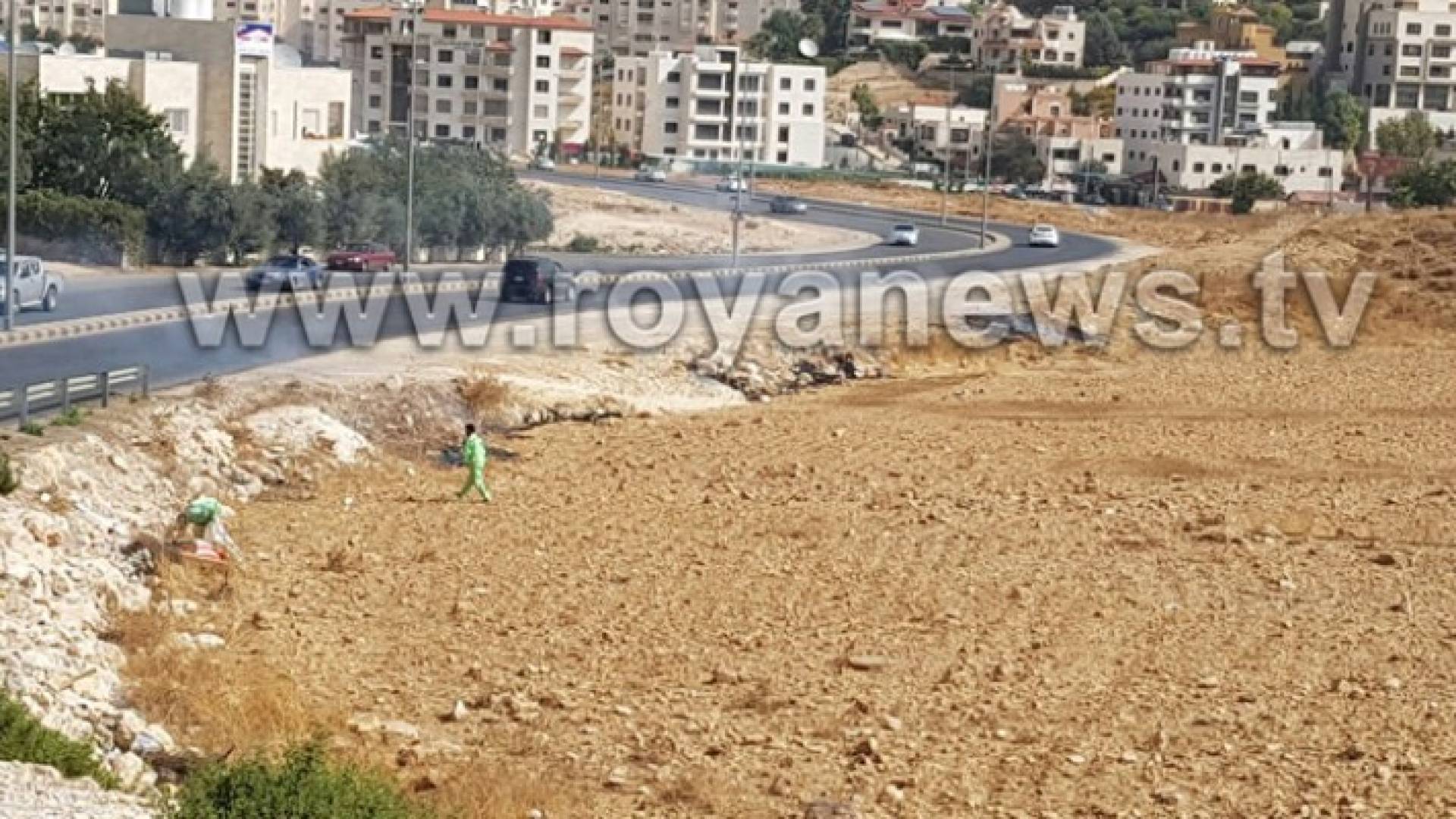 عمال وطن يقومون بإحراق النفايات على قارعة الطريق 