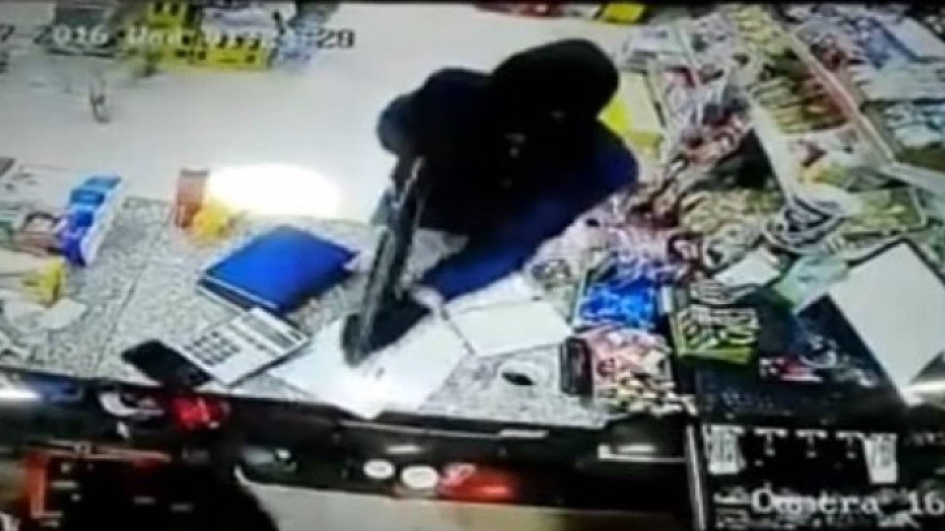 أحد أفراد العصابة يشهر سلاحه مهددا صاحب المتجر