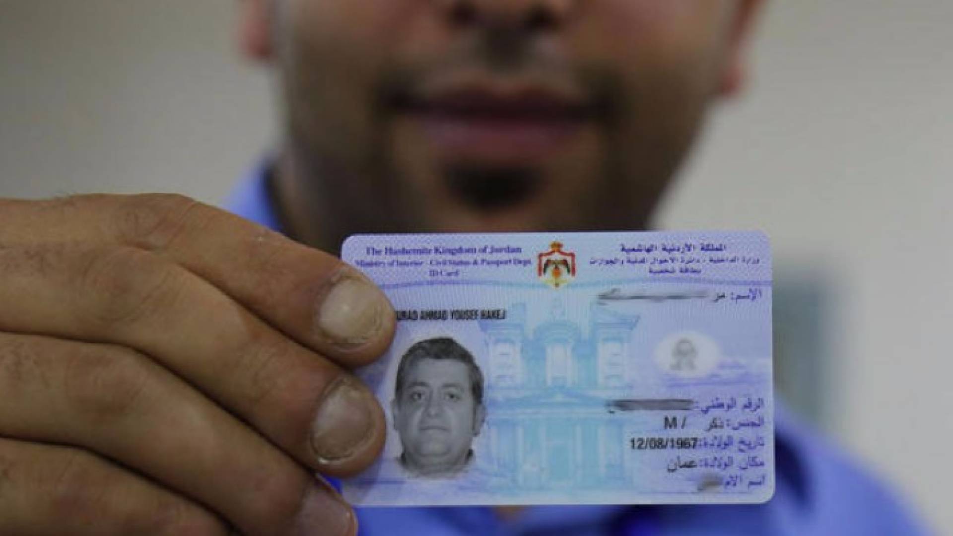 .. شاب يحمل بطاقته الذكية في دائرة الأحوال المدنية-ارشيف