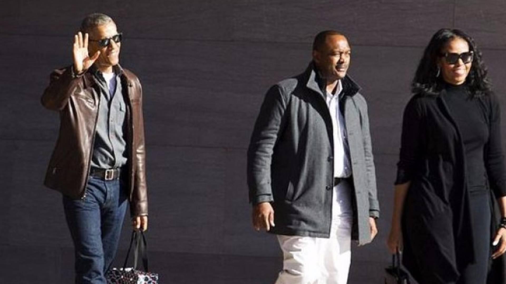 أوباما يرفع يده للتحية وإلى جانبه زوجته ميشيل