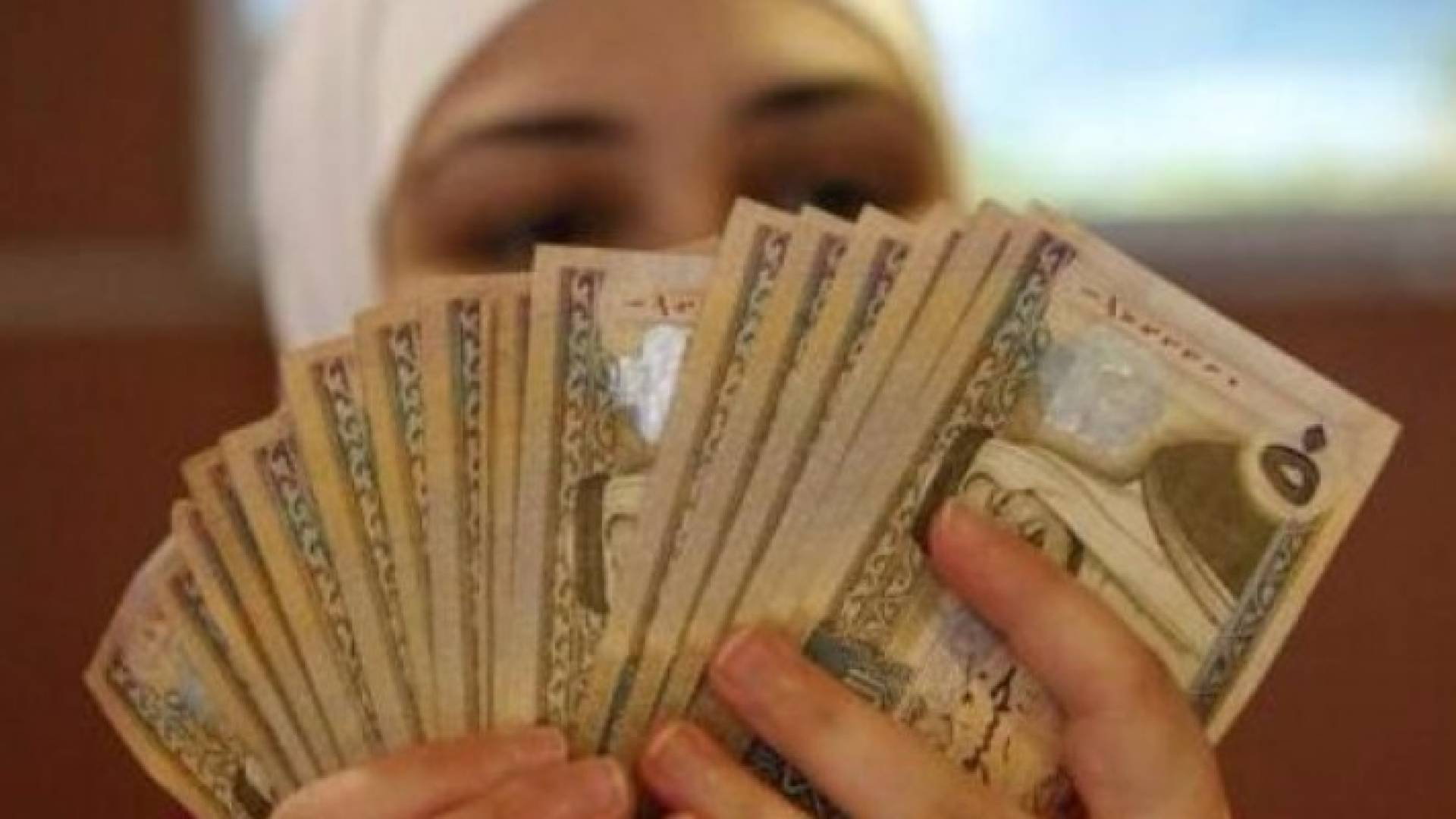 موظفة تعد أوراق نقد من الدينار الأردني