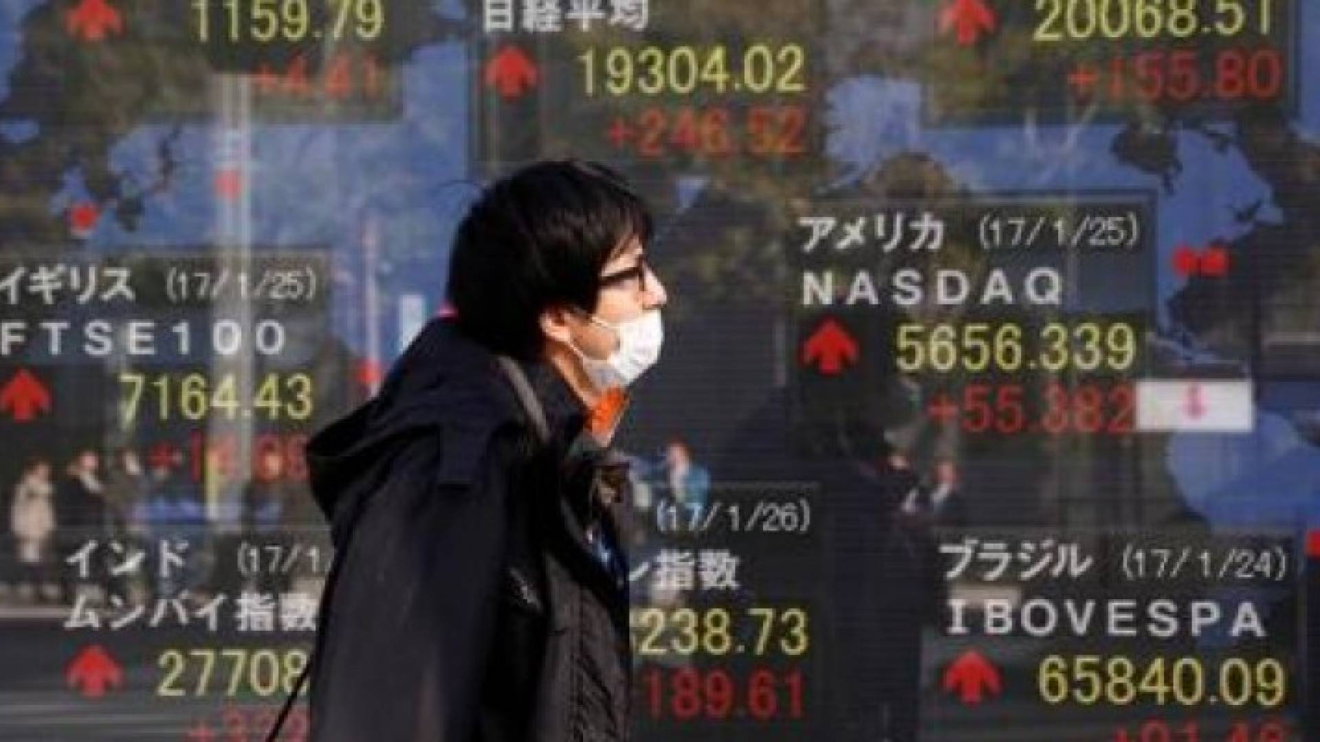 رجل يمر بلوحة تعرض مؤشرات أسواق مختلفة من ضمنها مؤشر نيكي  