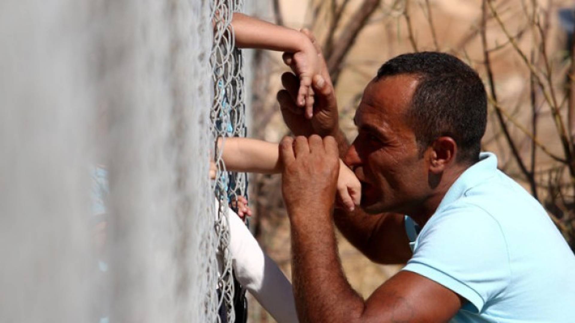 السوري عمار حمشو يقبل يد أبنائه عبر سياج في قبرص