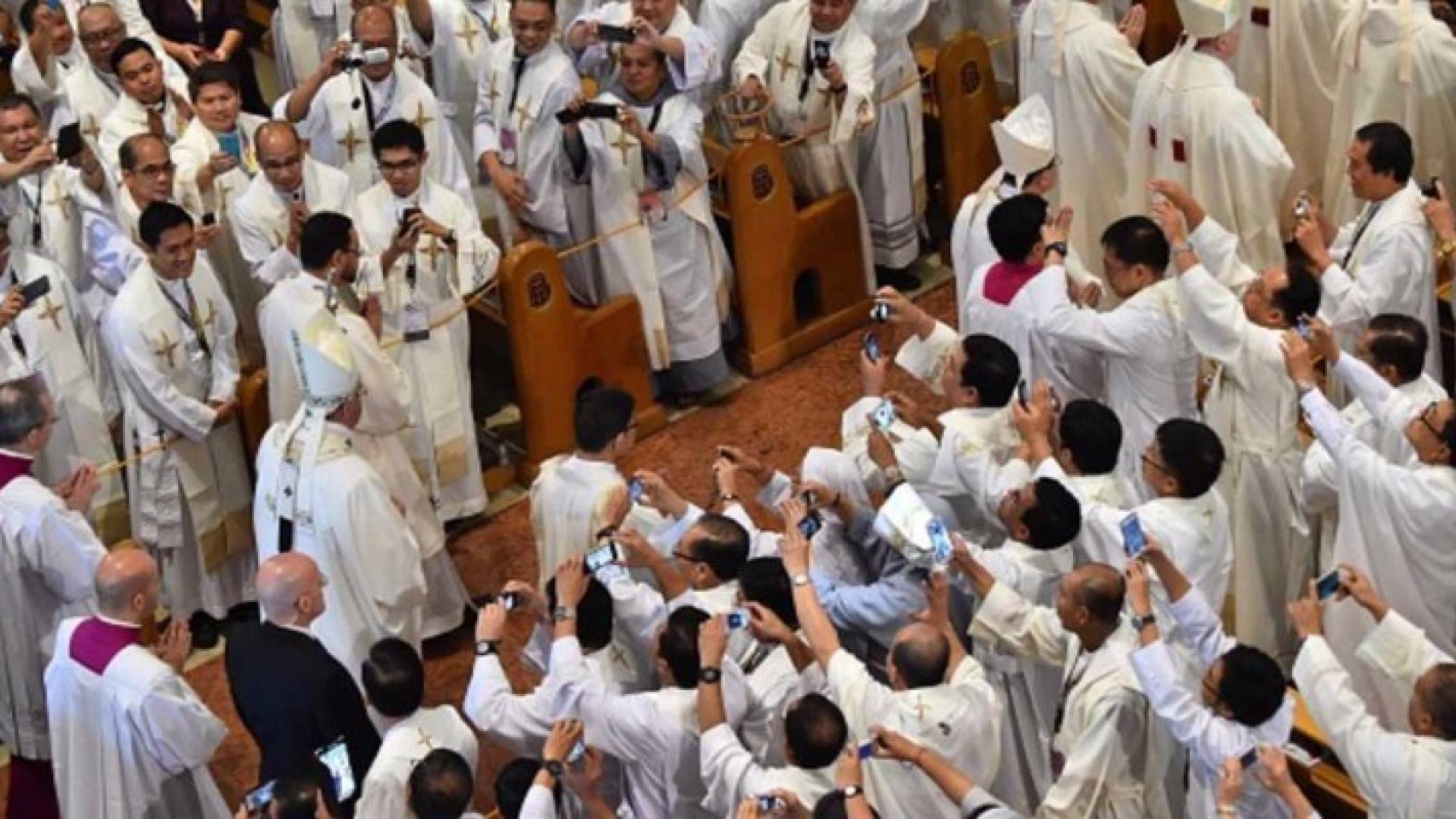 قساوسة يلتقوطون صورا للبابا فرنسيس خلال زيارة إلى الفلبين.