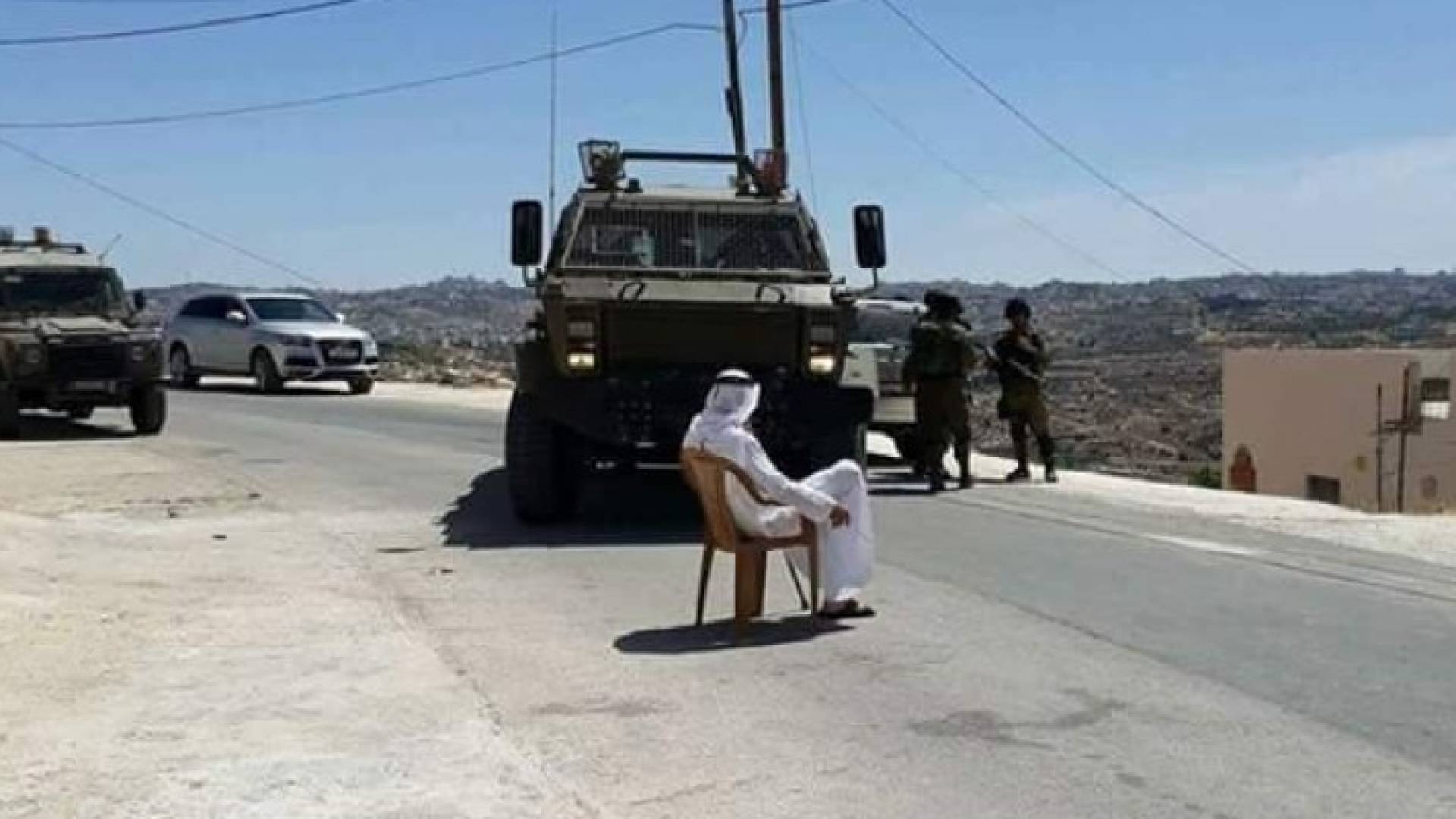 مسن فلسطيني يجلس أمام الآلية العسكرية 