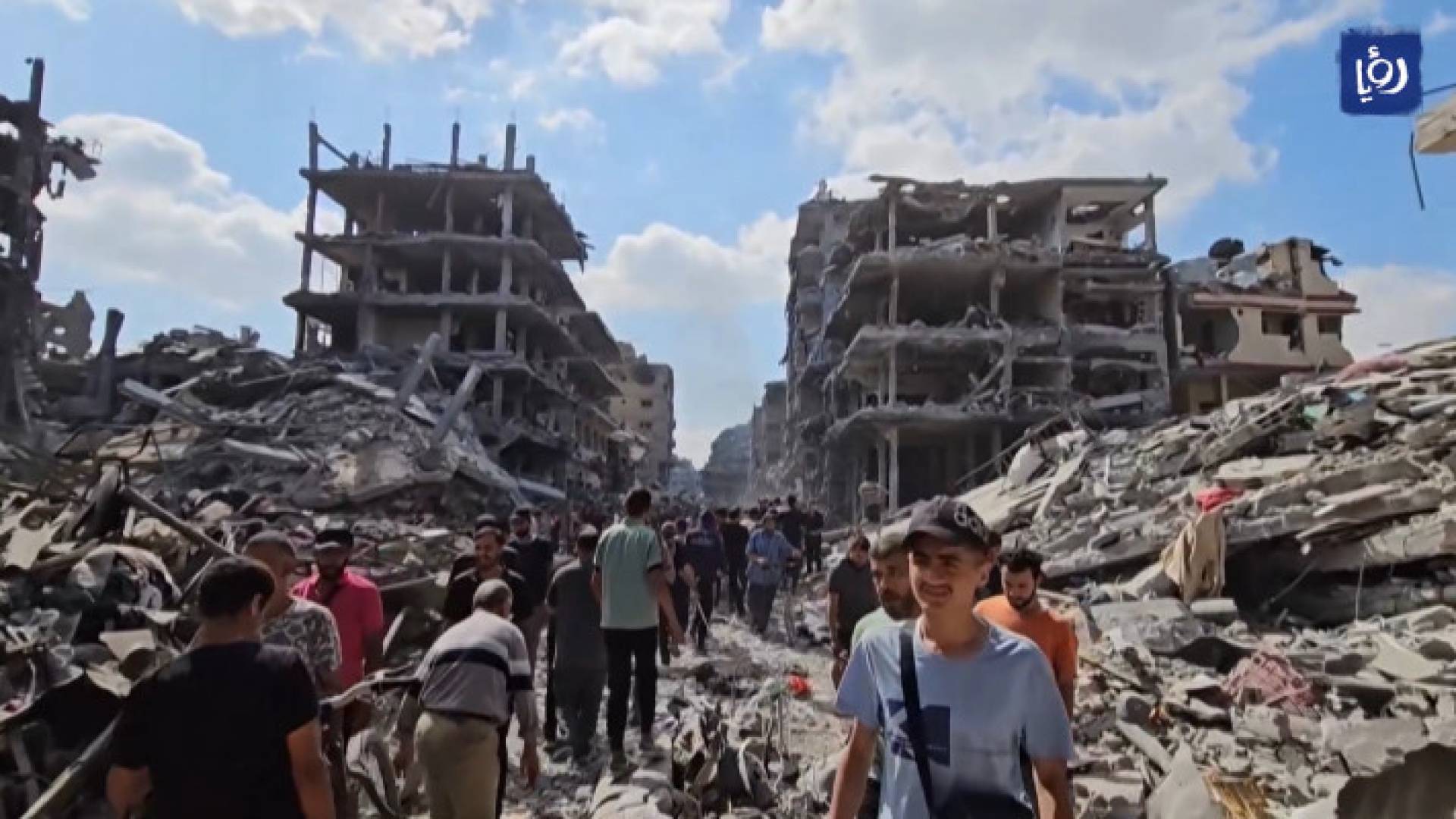 فلسطينيون يسيرون وسط ركان منازل دمرها عدوان الاحتلال في غزة