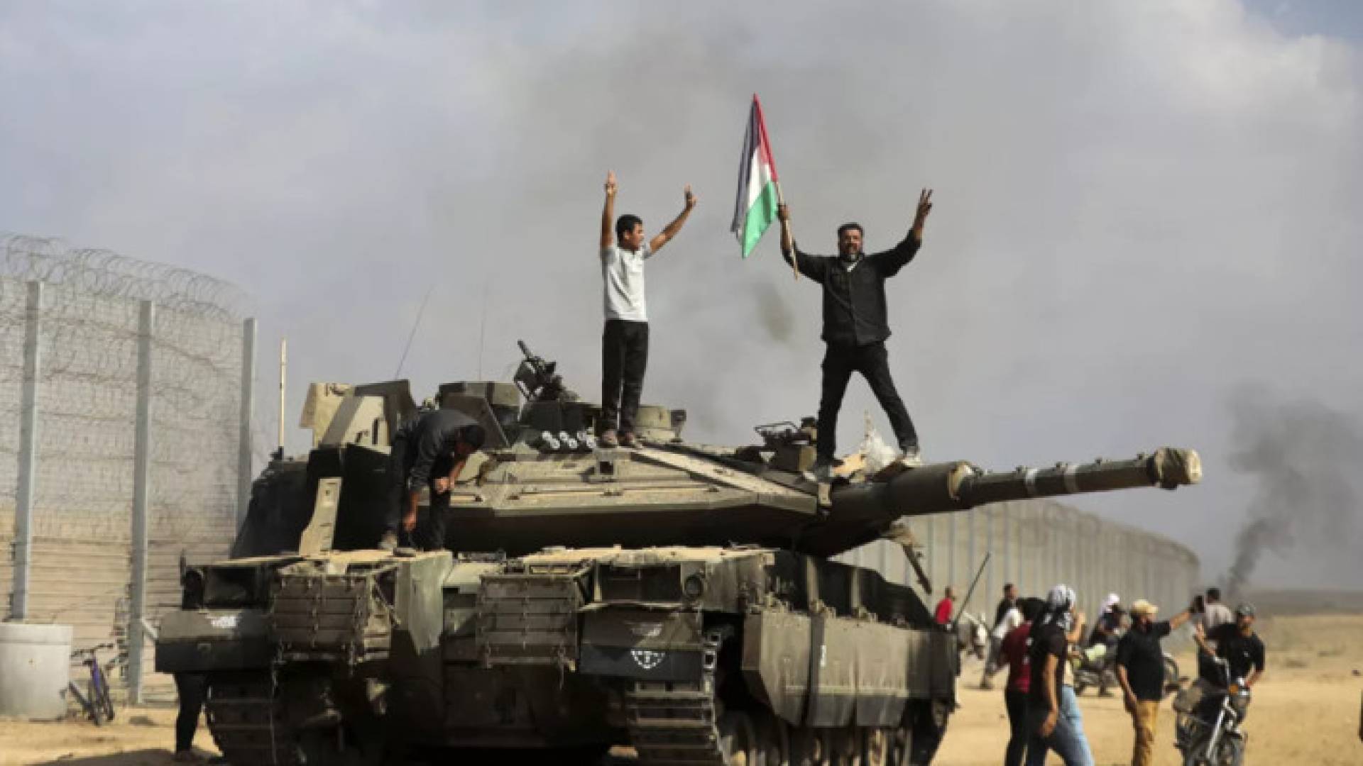 فلسطينيان برفعان علم دلتهم فوق دبابة للاحتلال