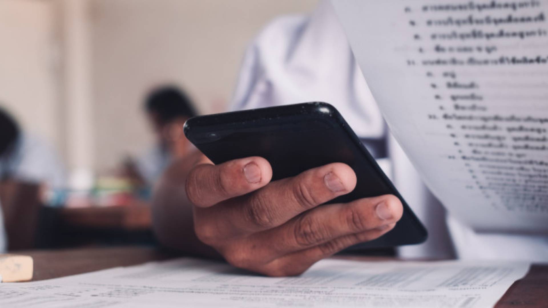 طالب يستخدم الهاتف الذكي خلال انعقاد امتحان