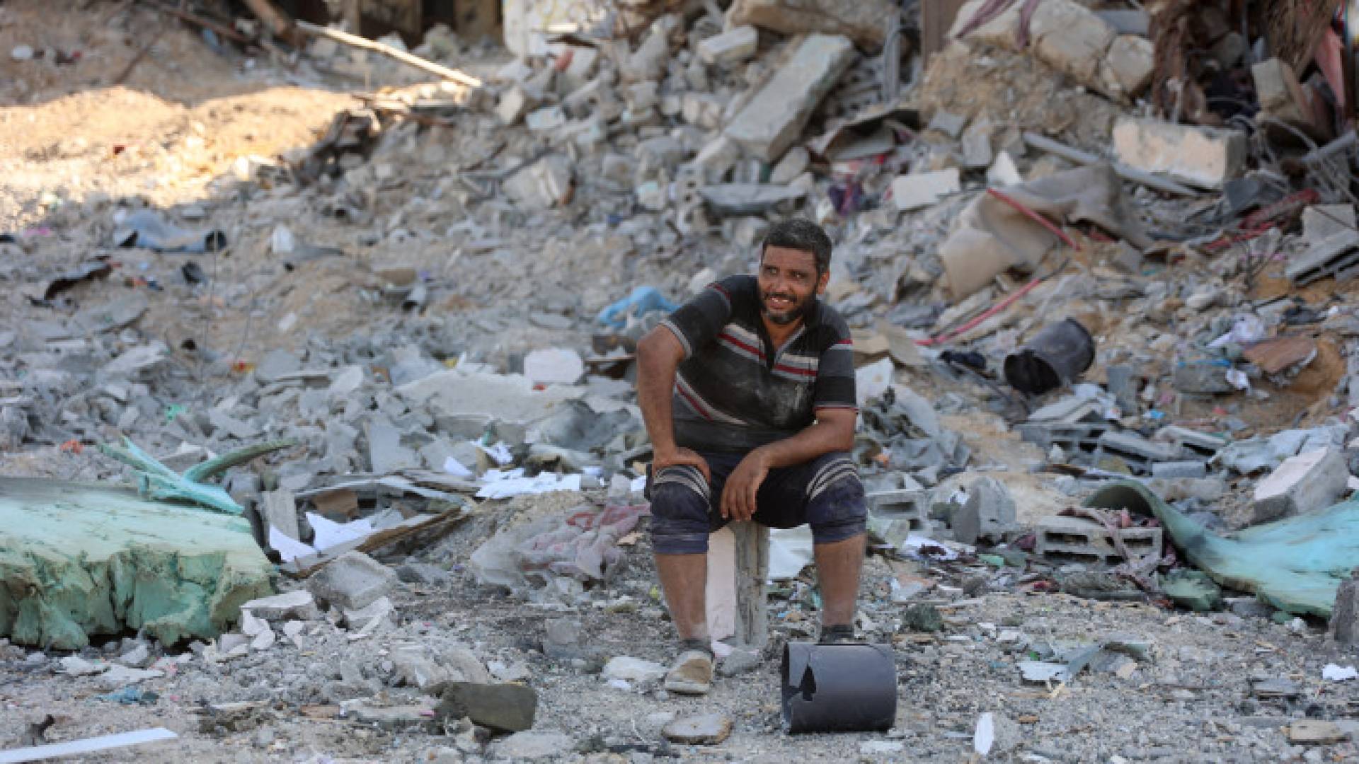 فلسطيني يجلس على ركام منزله ويبتسم رغم الجراح في غزة