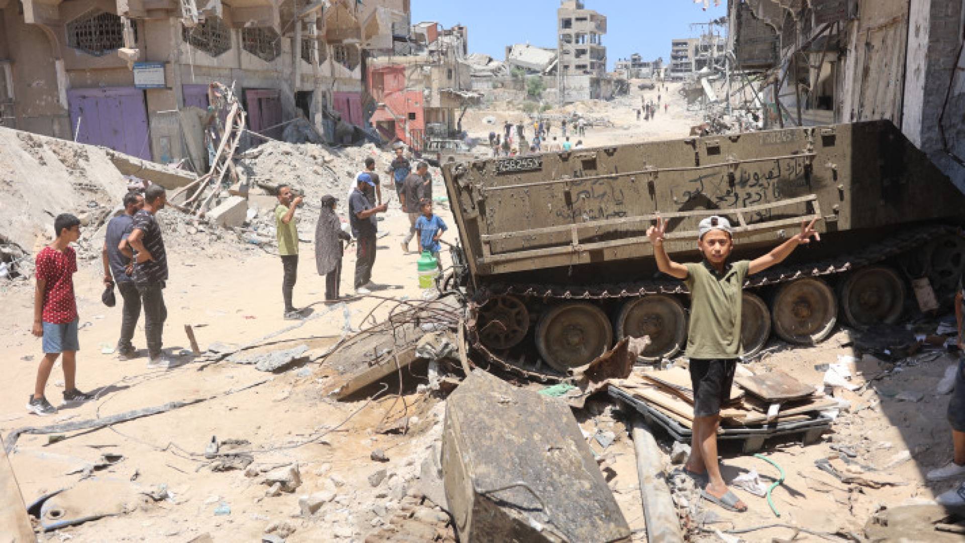 فتى فلسطيني يرفع علامة النصر بالقرب من دبابة للاحتلال الإسرائيلي