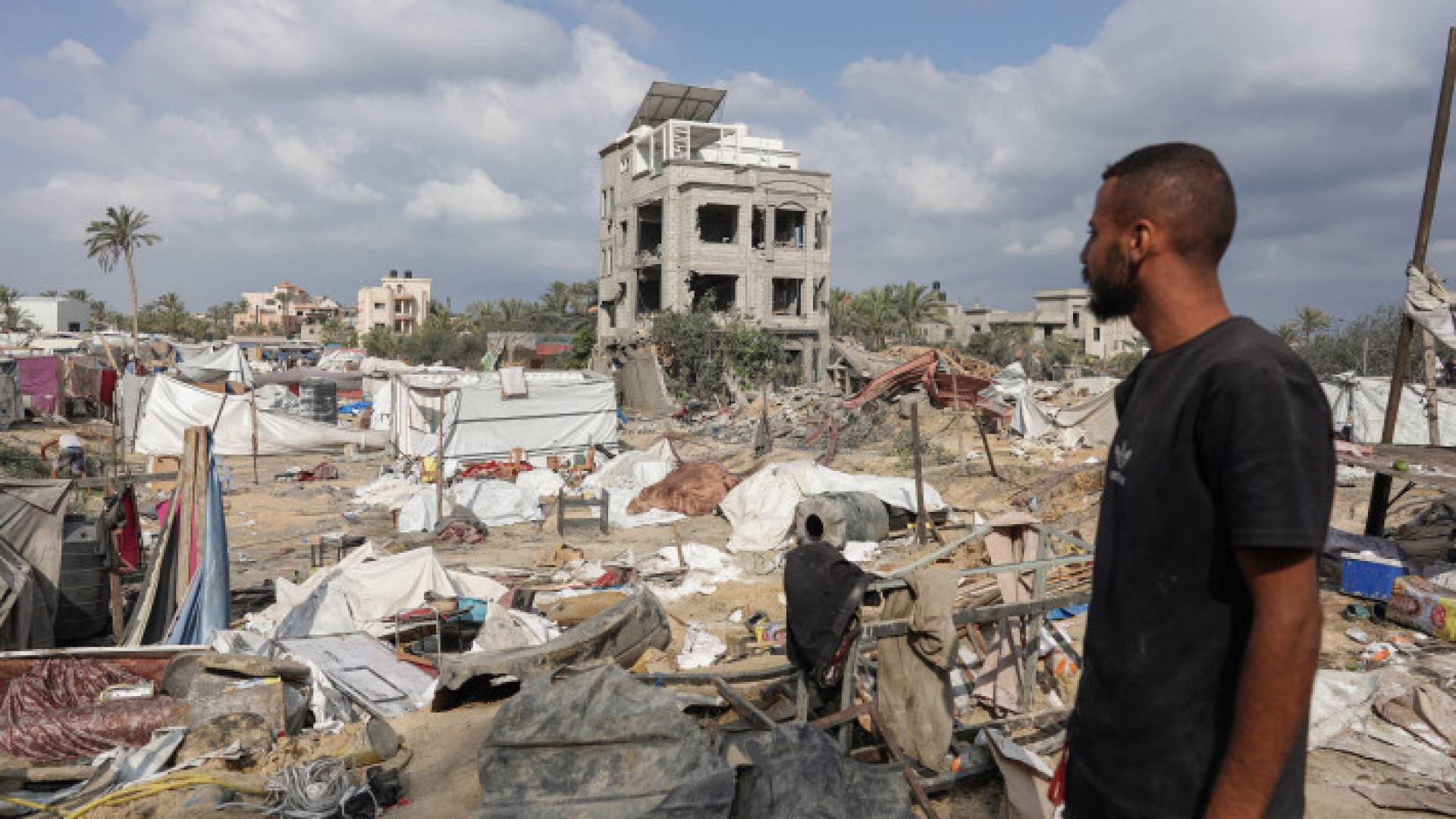 شاب  فلسطيني ينظر إلى الخيام المتضررة في قصف للاحتلال على مخيم المواصي للنازحين في مدينة خان يونس