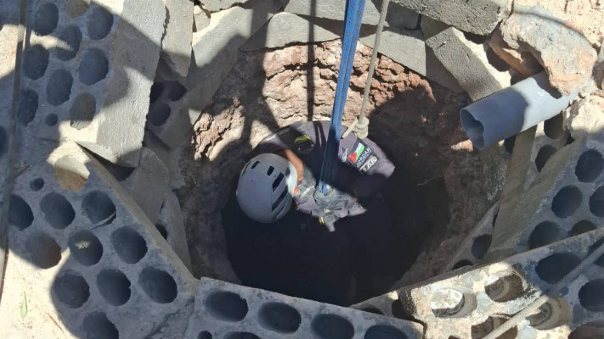 أحد كوادر الدفاع المدني يدخل إلى البئر لإنقاذ المصاب الذي سقط فيه