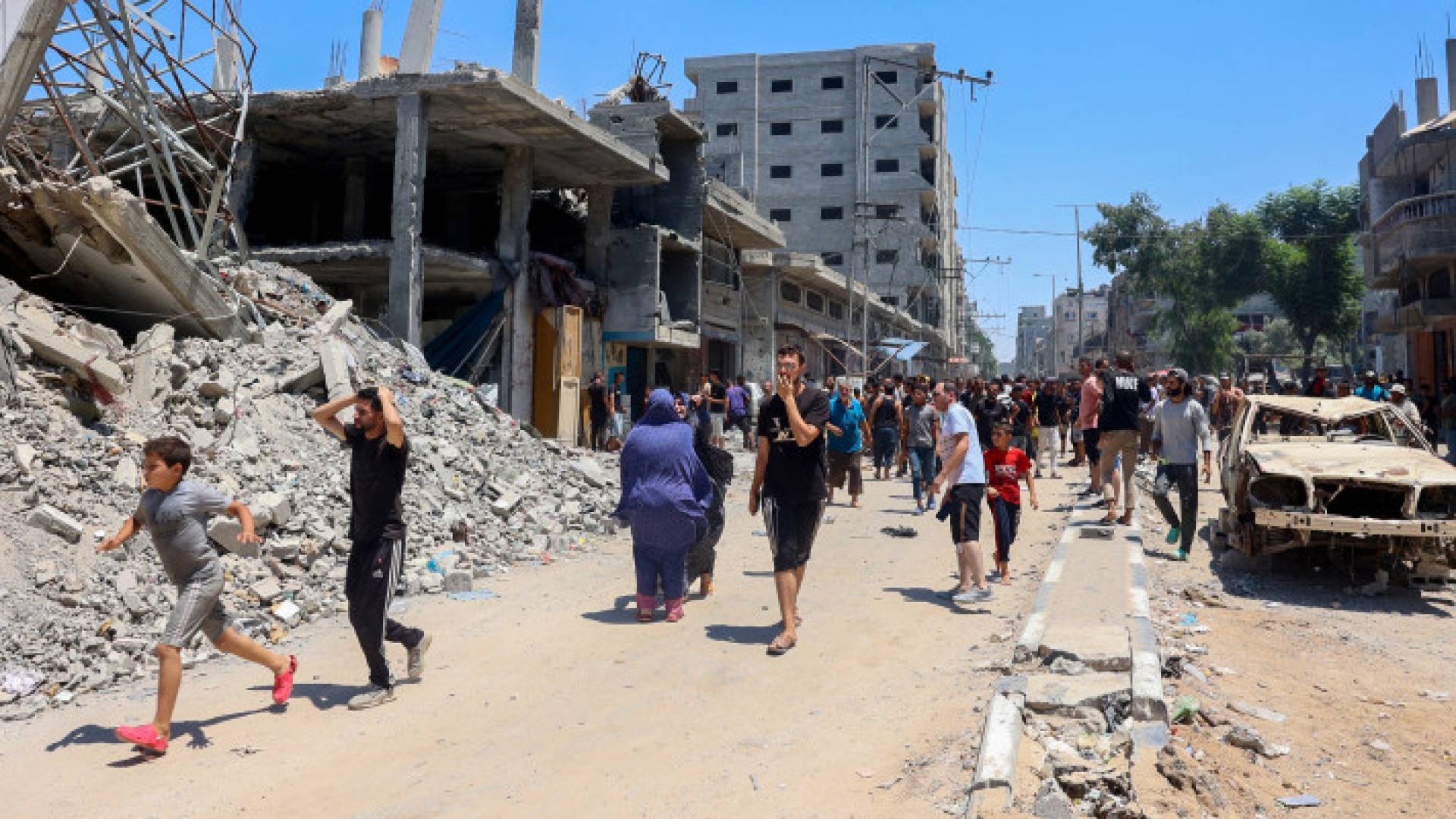 فلسطينيون وسط الدمار الذي خلفه قصف الاحتلال في مخيم البريج للاجئين في وسط قطاع غزة