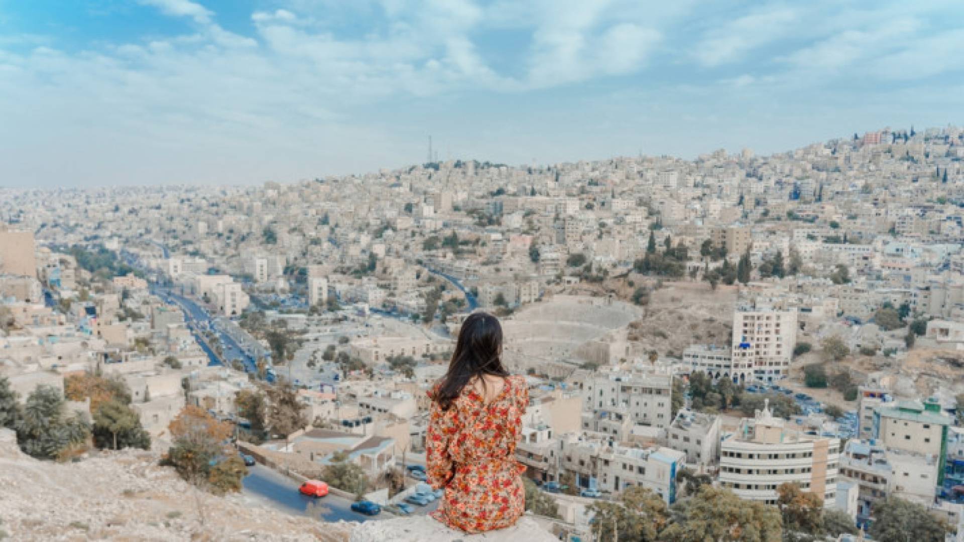 شابة تنظر إلى العاصمة عمان من جبل القلعة