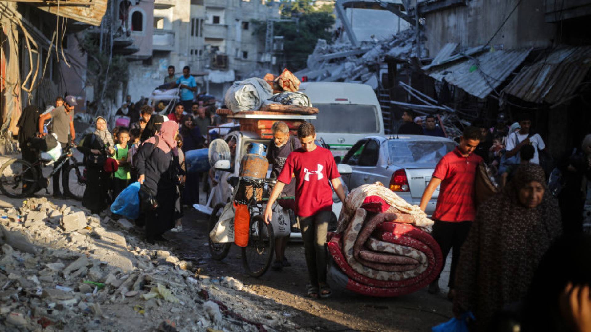 فلسطينيون يحملون متعلقاتهم  في مخيم البريج في وسط قطاع