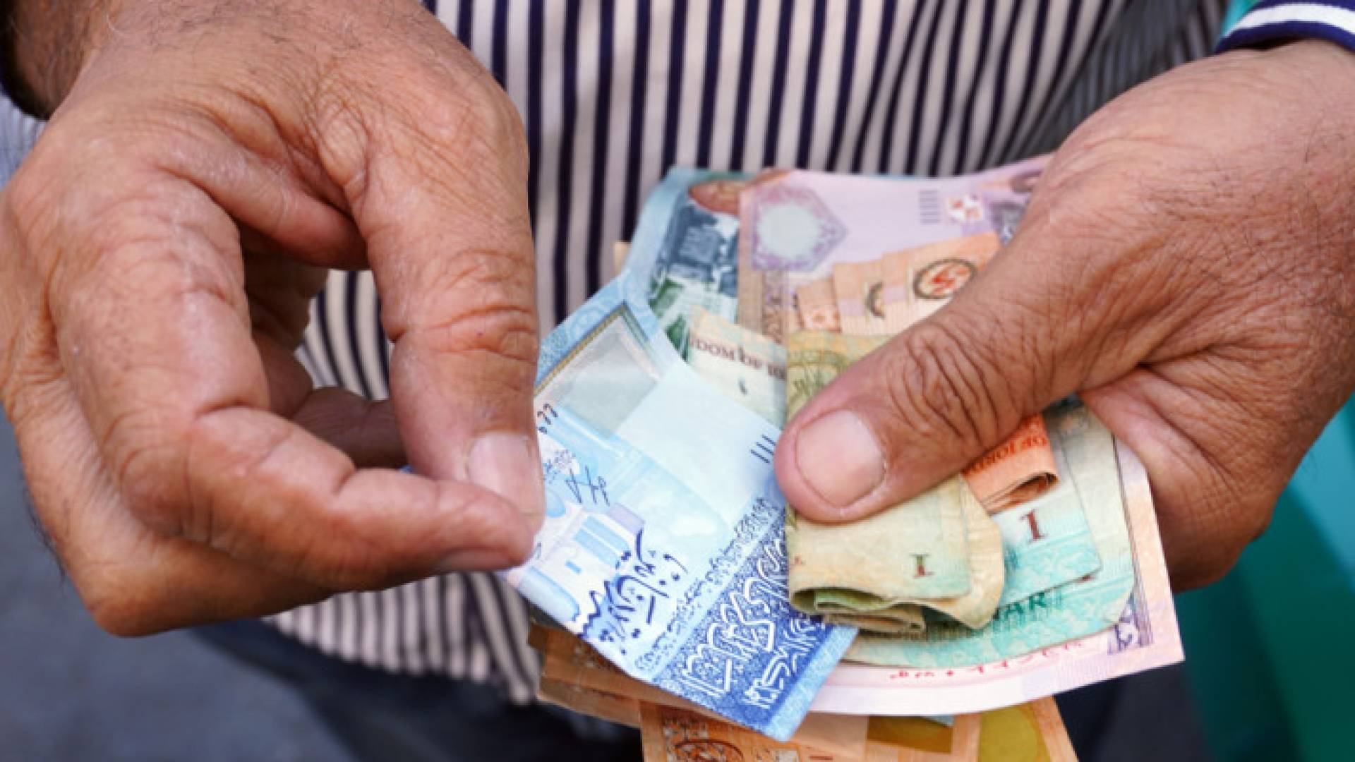 شخص يحمل عملة ورقية أردنية