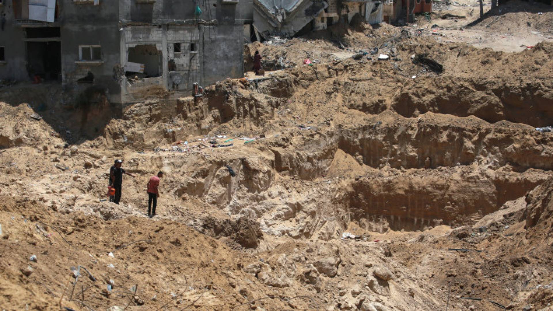 فلسطينيون ينظرون إلى الدمار الذي تسبب به جيش الاحتلال في بلدة بني سهيلة شرق خان يونس جنوبي قطاع غزة