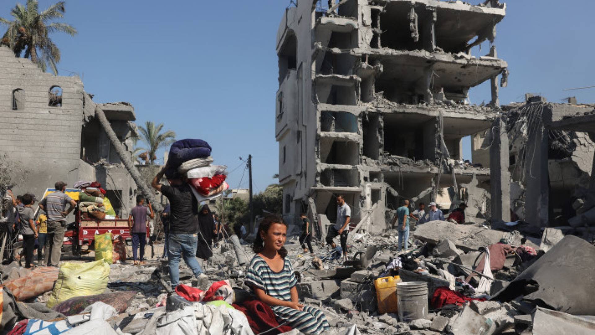 فتاة فلسطينية تجلس بينما يستعيد الناس ممتلكاتهم في دير البلح بوسط قطاع غزة