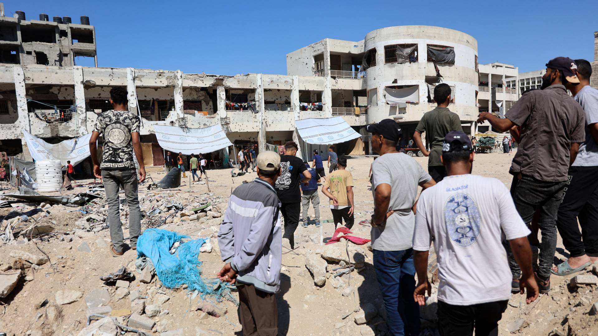 فلسطينيون يقفون وسط الدمار في مدرسة الزهراء