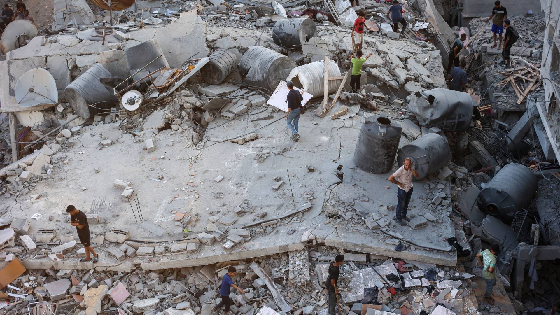 أشخاص يتفقدون الأضرار في حي الشيخ رضوان بمدينة غزة