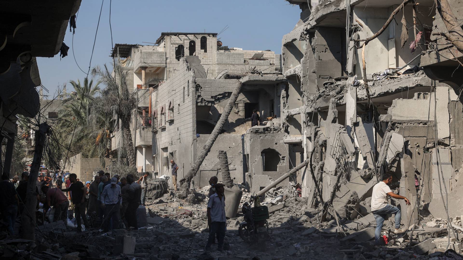 فلسطينيون على انقاض مبان دمرت في دير البلح وسط قطاع غزة