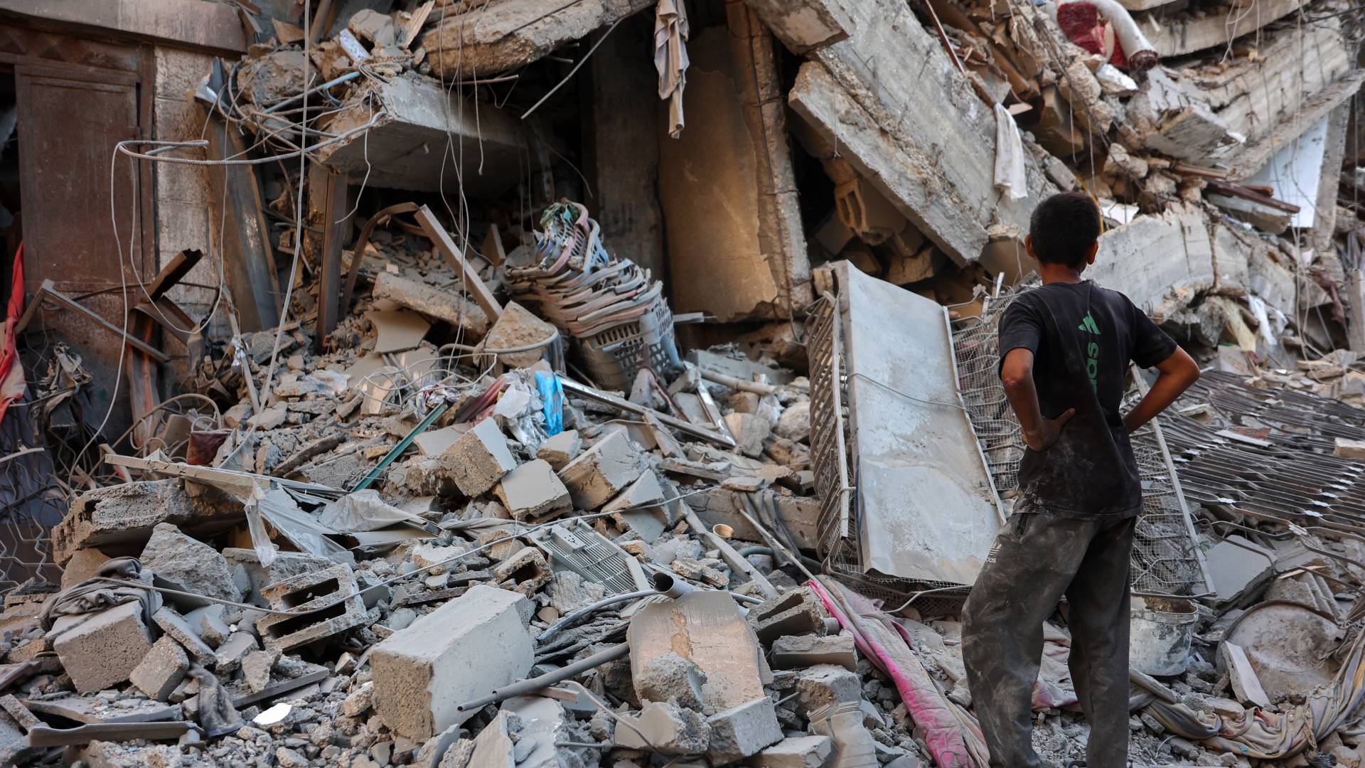 فتى فلسطيني ينظر إلى مبنى دمره قصف الاحتلال في حي الشيخ رضوان بمدينة غزة