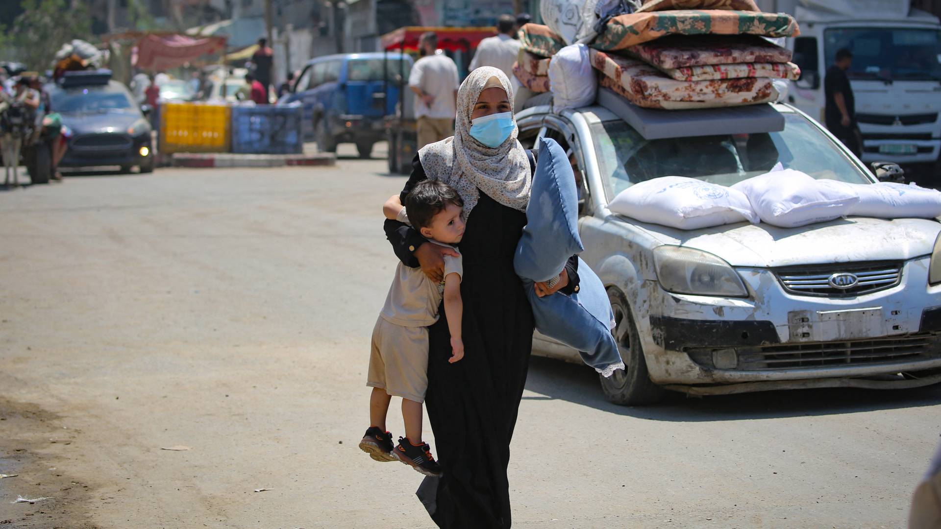 فلسطينية تحمل طفلها وتبحث عن مأوى آمن في غزة