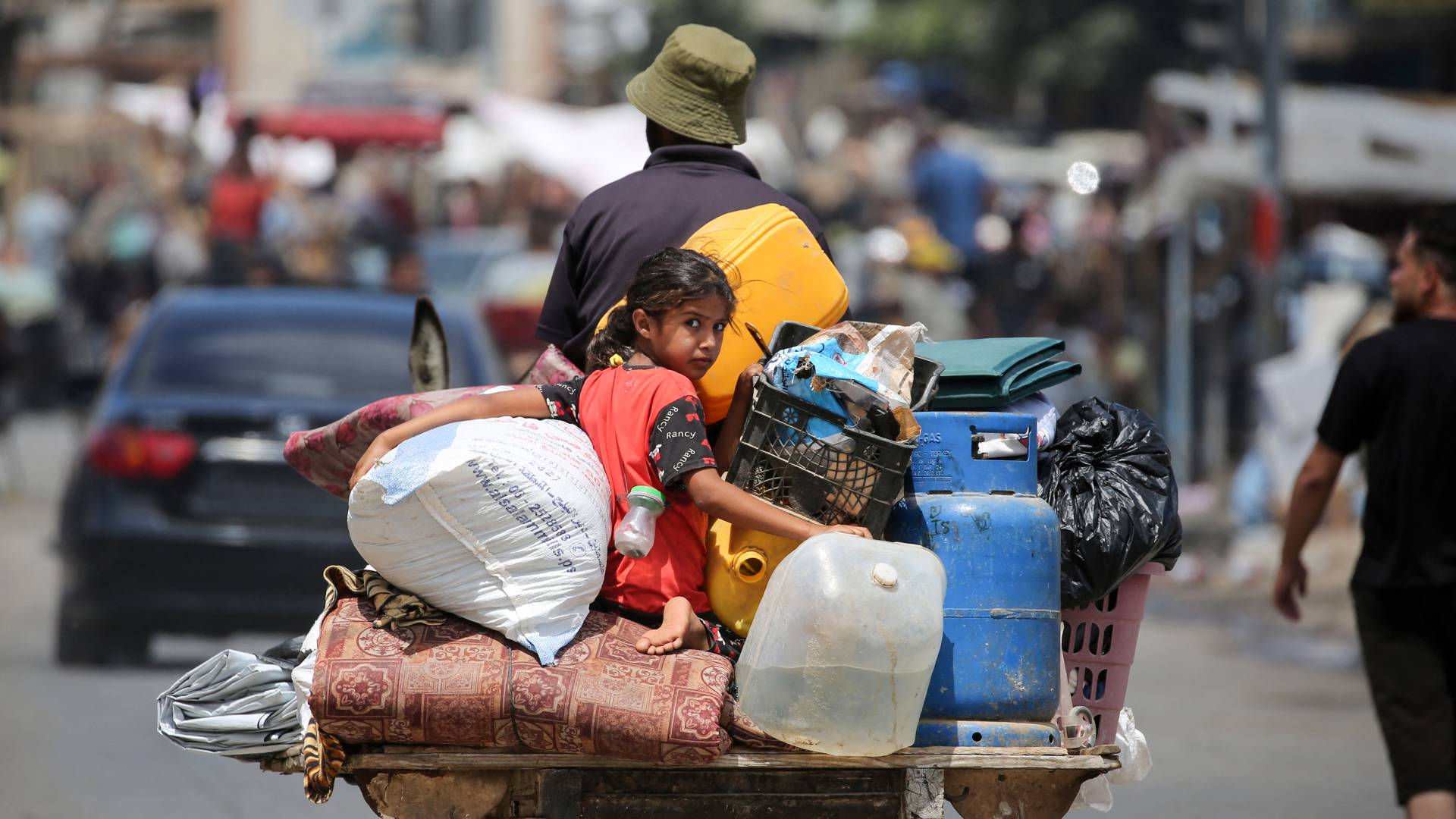 طفلm يجلس فوق عربة يجرها حمار بينما يفر الفلسطينيون بممتلكاتهم من دير البلح في وسط قطاع غزة