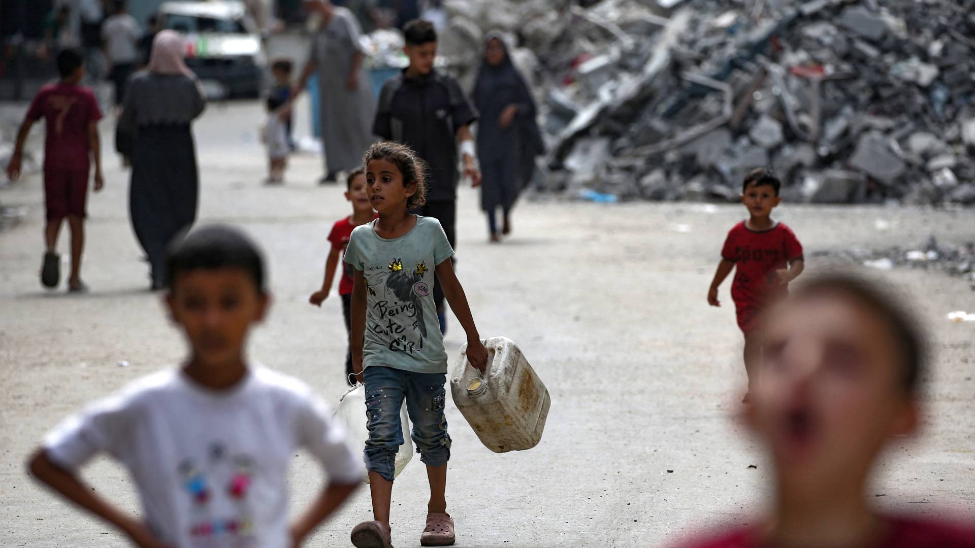 طفلm فلسطيني يسير باتجاه نقطة توزيع المياه في مخيم البريج للاجئين في وسط قطاع غزة