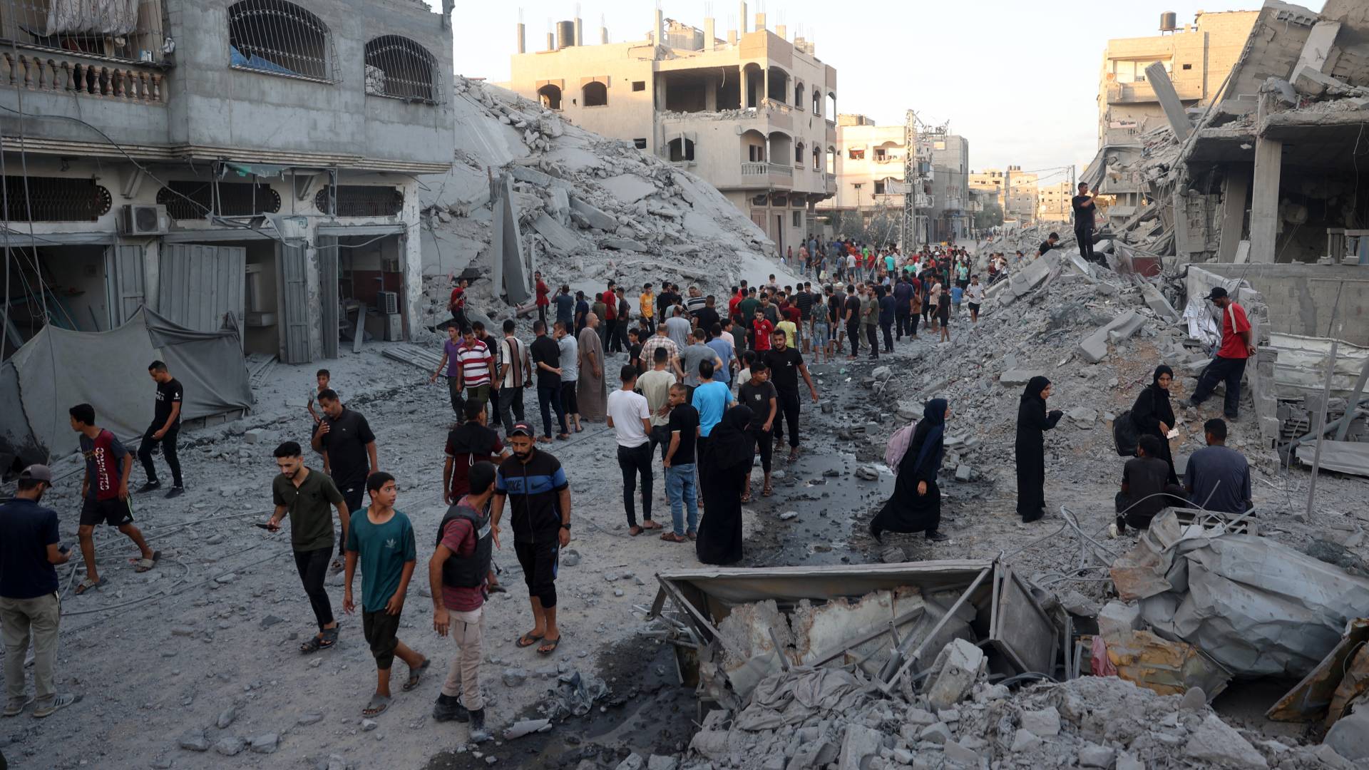 فلسطينيون وسط الدمار الذي خلفه الاحتلال في مخيم النصيرات في وسط قطاع غزة