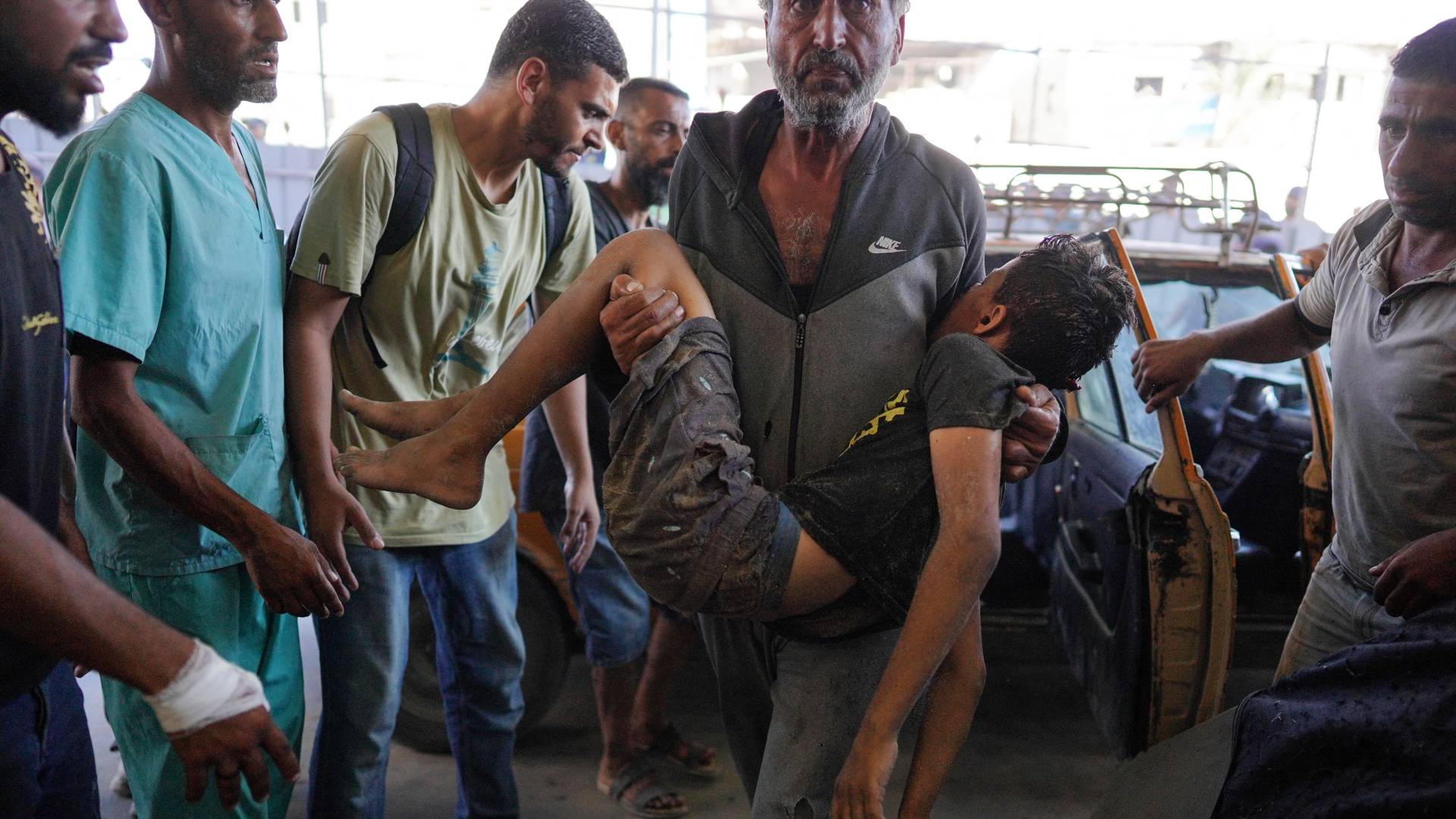 فلسطيني يحمل فتى مصاب بقصف للاحتلال في غزة