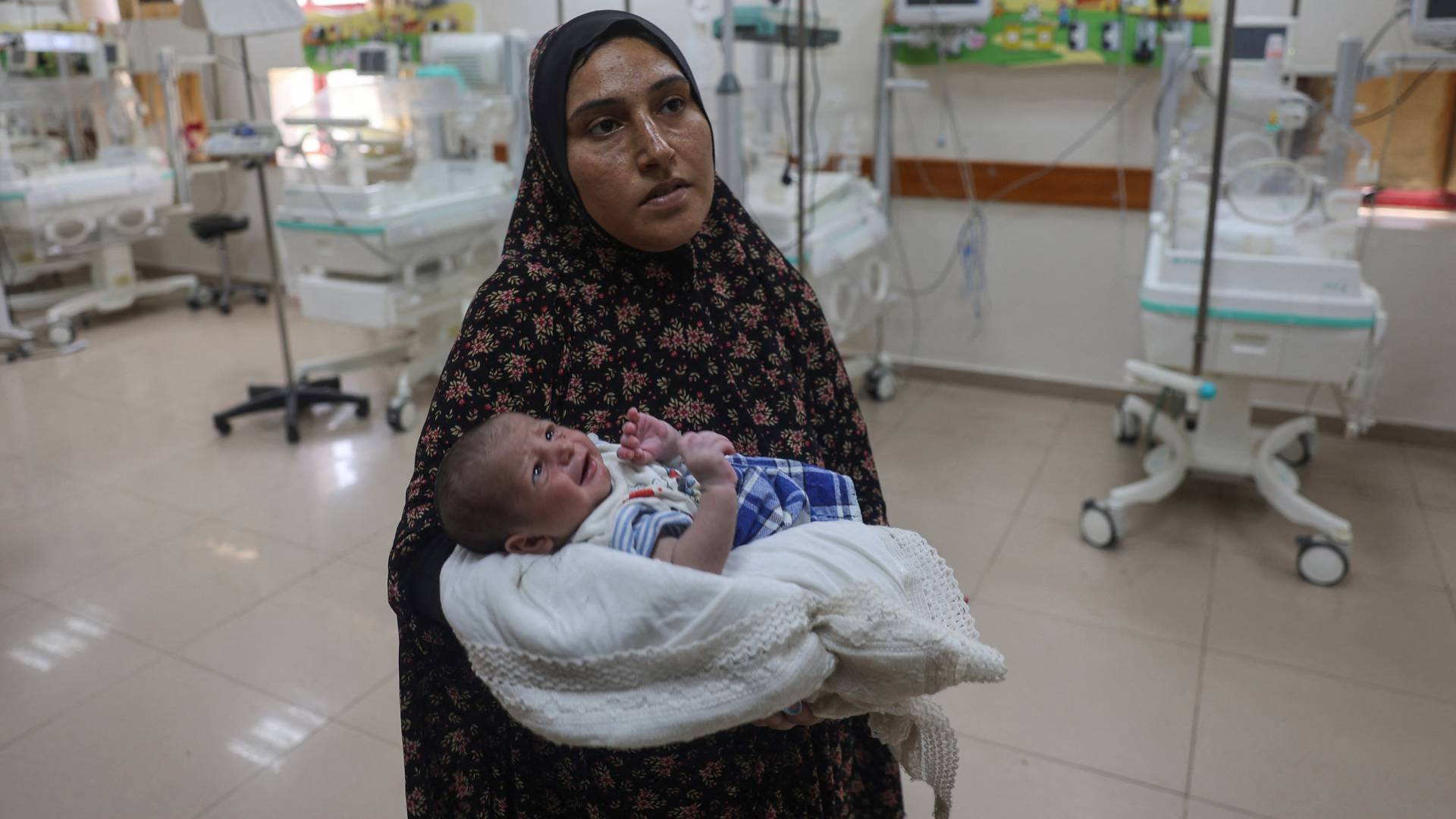 فلسطينية تحمل طفلها الصغير في غزة