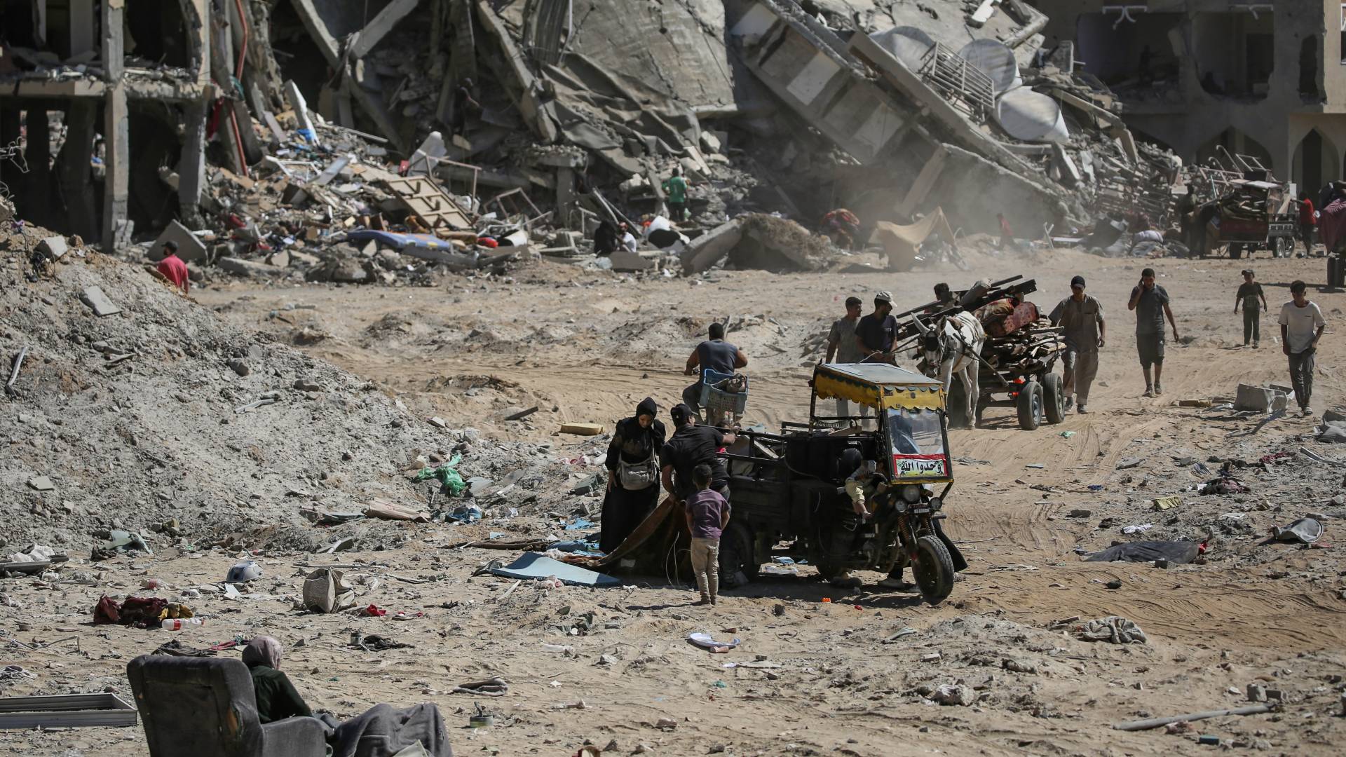 الفلسطينيون الذين عادوا لفترة وجيزة إلى شرق دير البلح وسط قطاع غزة  يحملون بعض العناصر التي تمكنوا من إنقاذها وسط الدمار