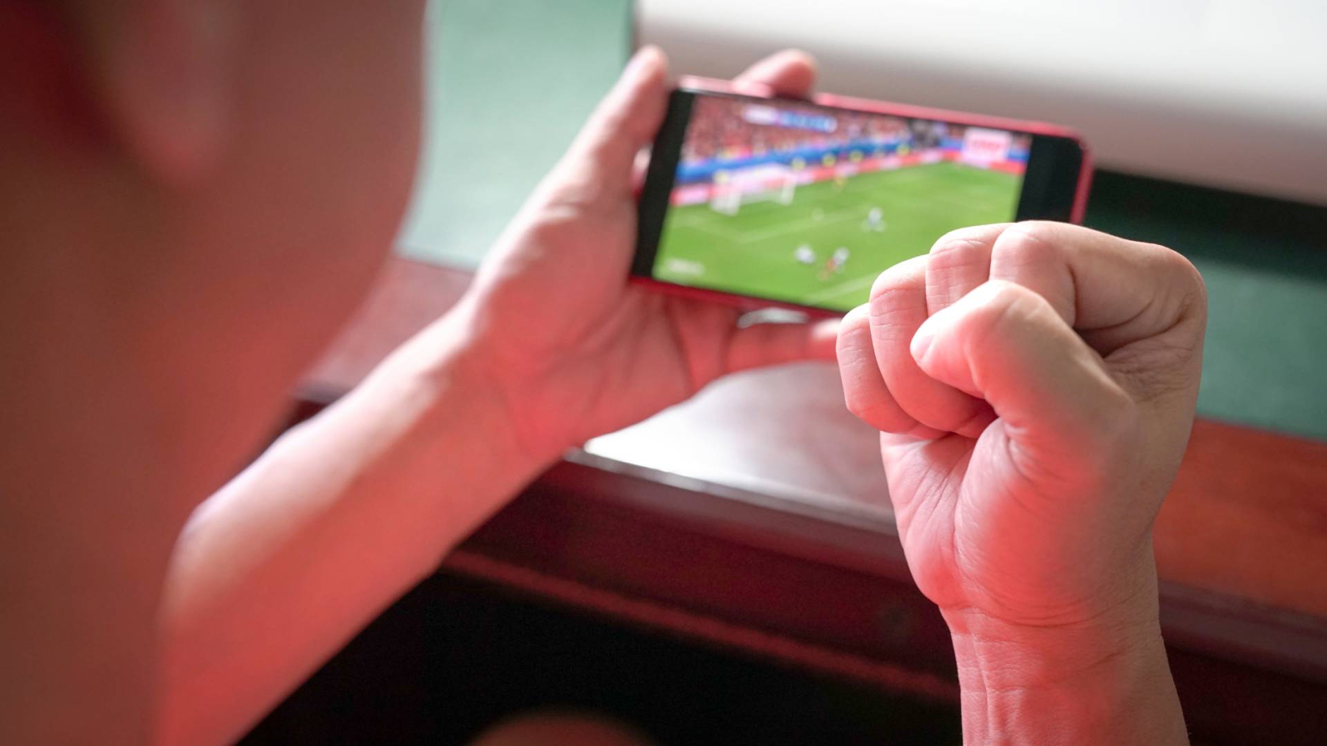 شاب يتابع مباراة عبر الهاتف المحمول