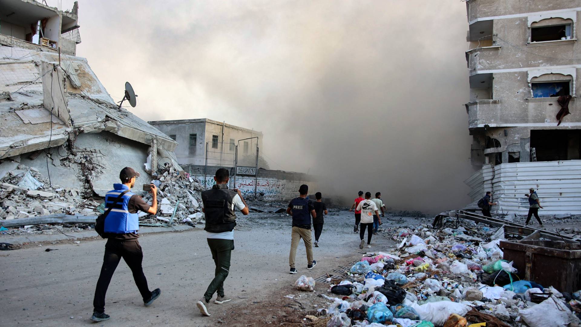 أشخاص وصحفي يندفعون نحو مكان انفجار في أعقاب غارة للاحتلال استهدفت مدرسة في حي الزيتون