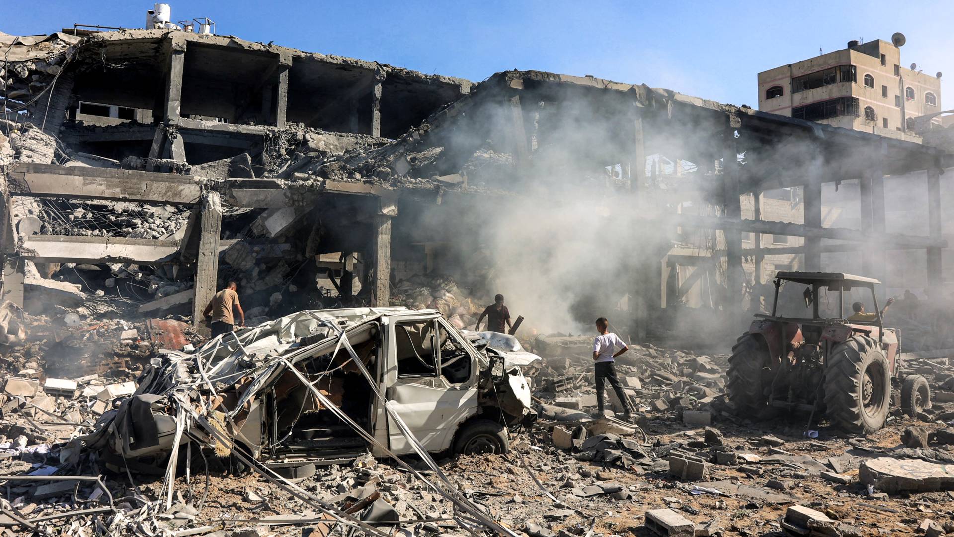 جال يسيرون عبر الأنقاض في مبنى تعرض لقصف الاحتلال في حي الشيخ رضوان شمال مدينة غزة