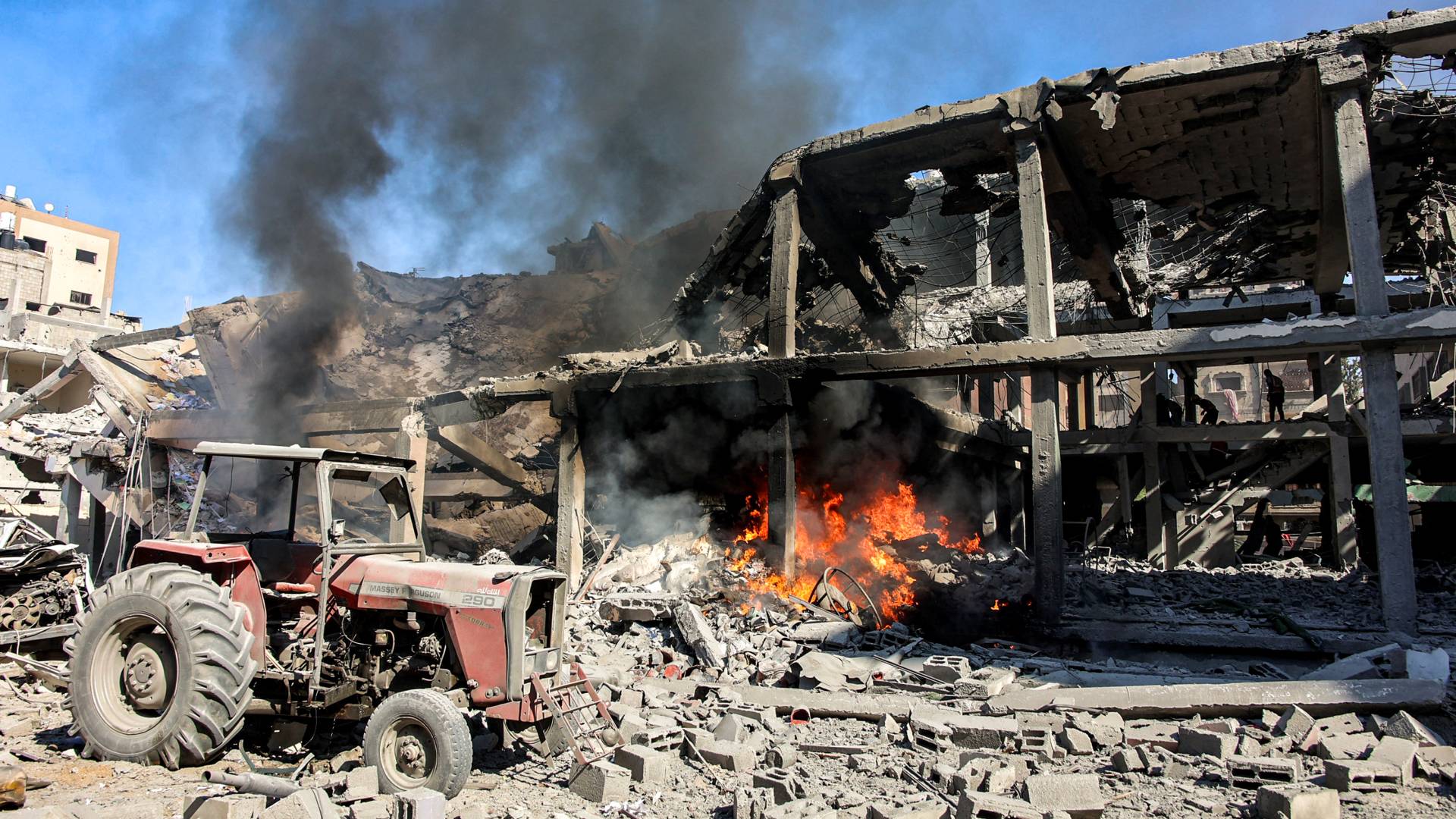 رجال يسيرون عبر الأنقاض في مبنى تعرض لقصف الاحتلال في حي الشيخ رضوان شمال مدينة غزة