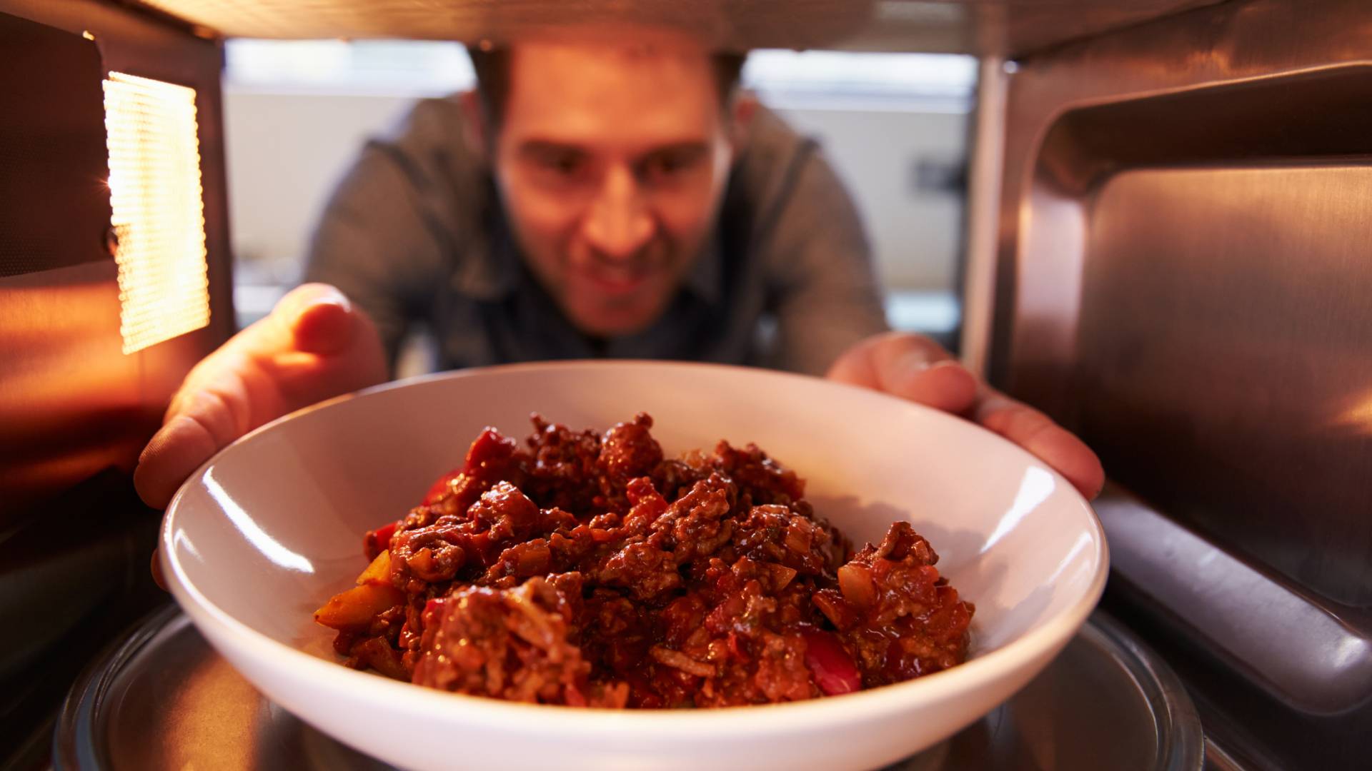 صورة شاب يقوم بتسخين وجبته في المايكروويف