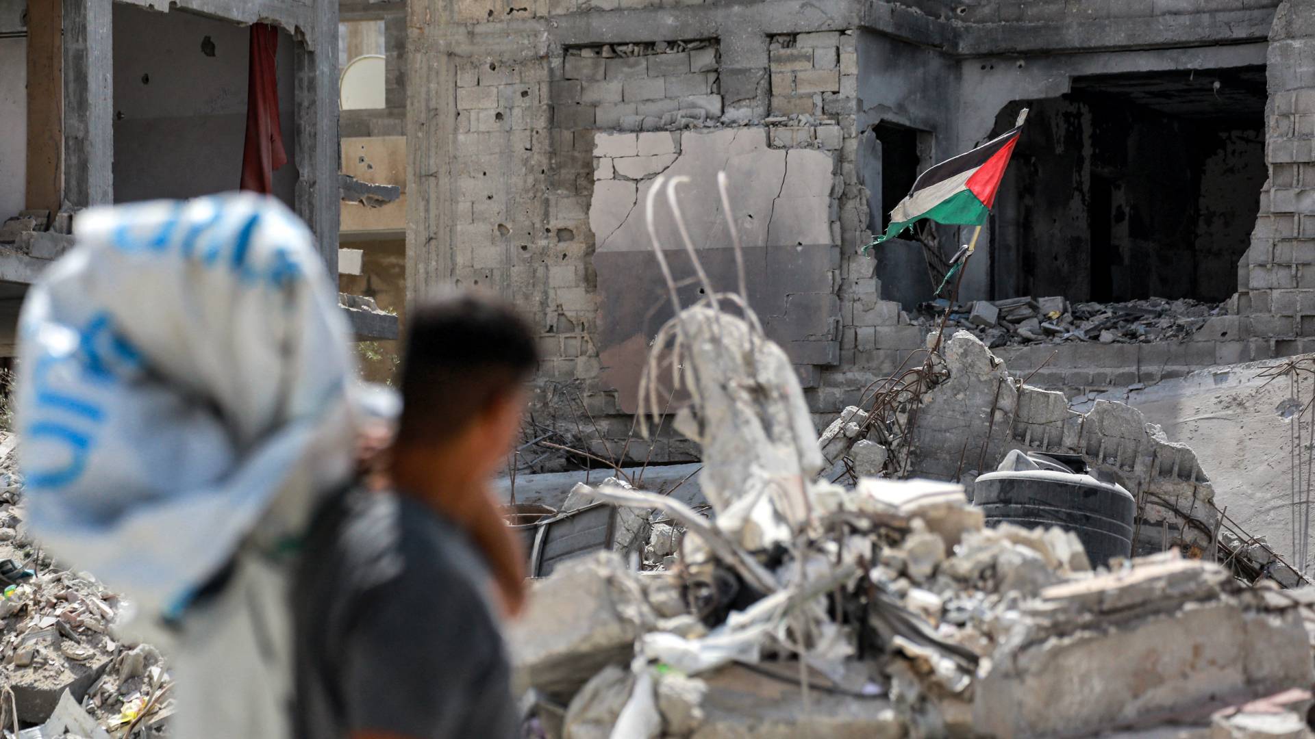 فلسطيني ينظر إلى علم بلاده المعلق بين الركام
