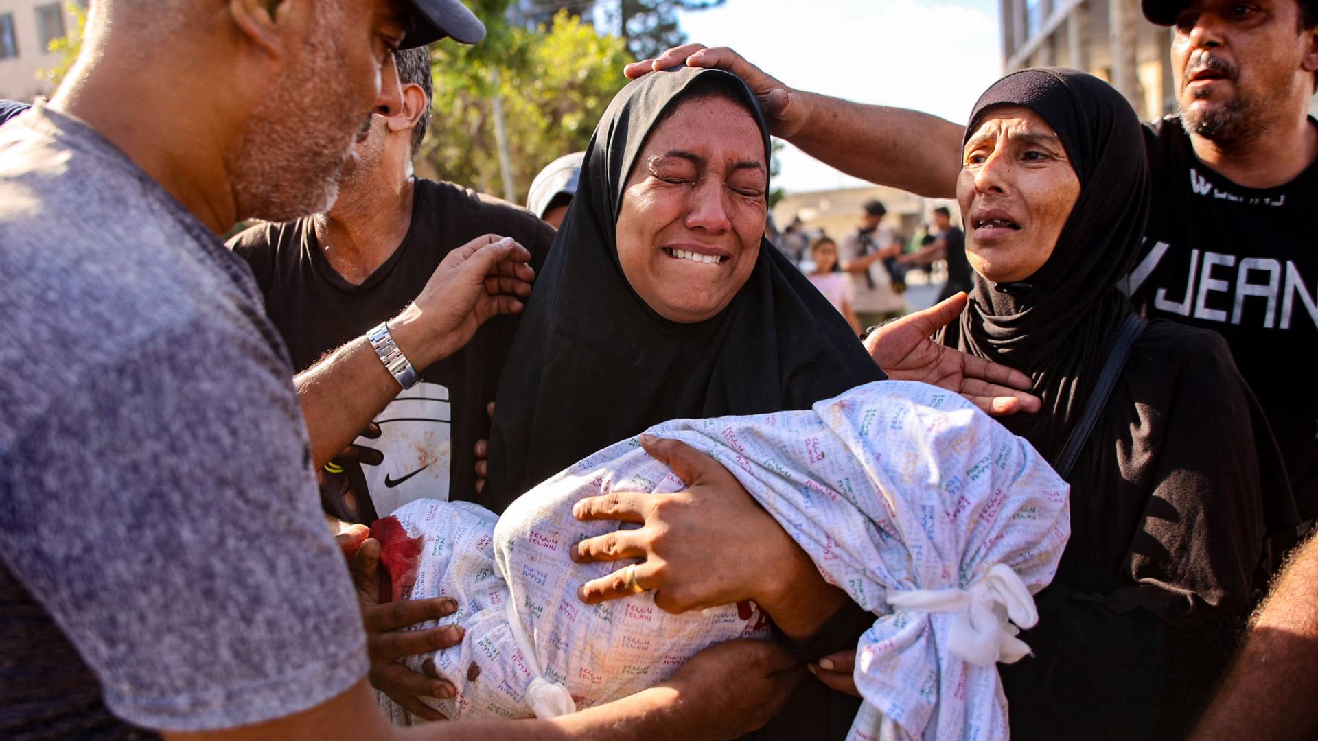فلسطينية تحمل رضيعها الشهيد في غزة