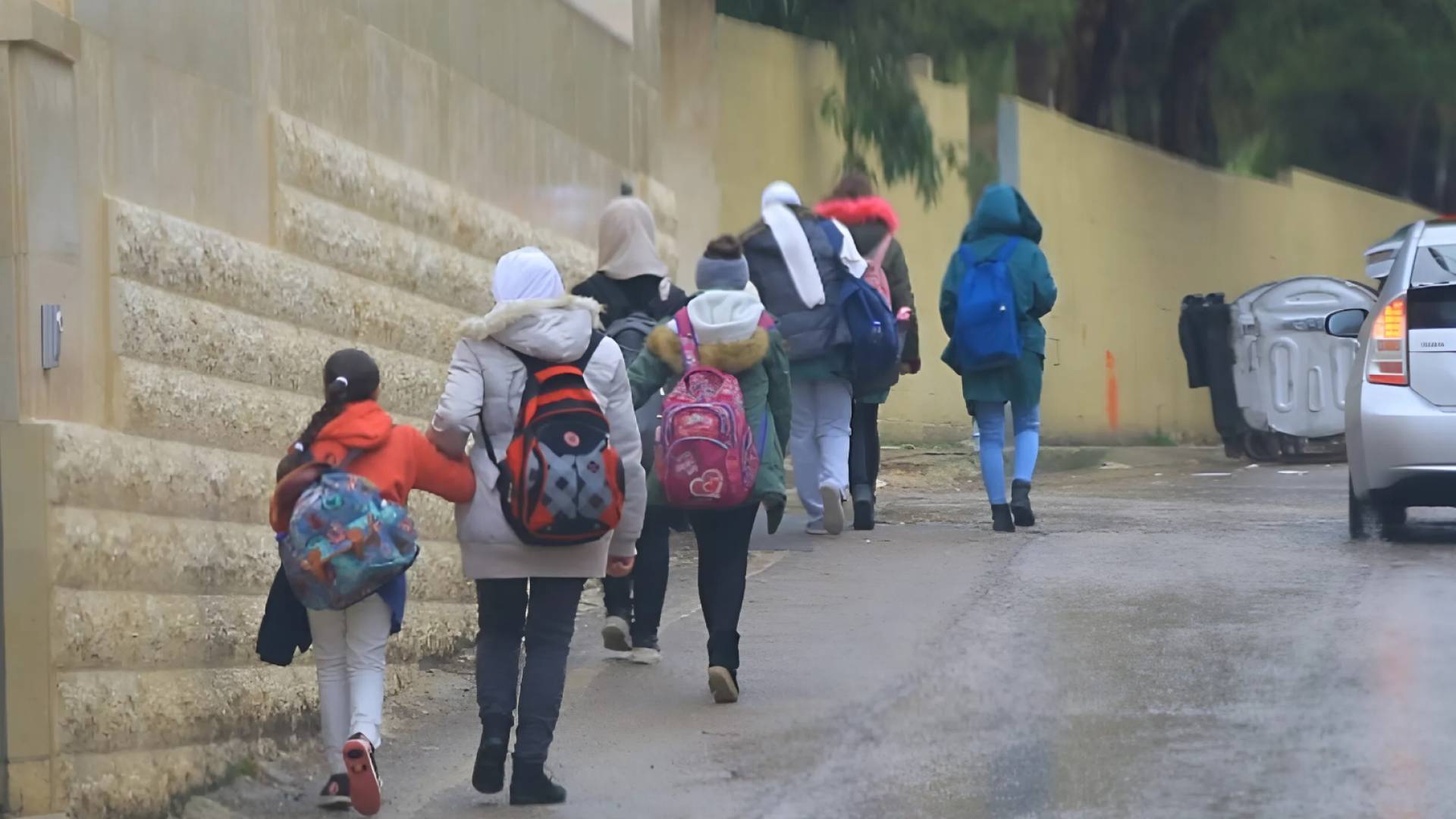 طالبات يسيرن في أجواء ماطرة