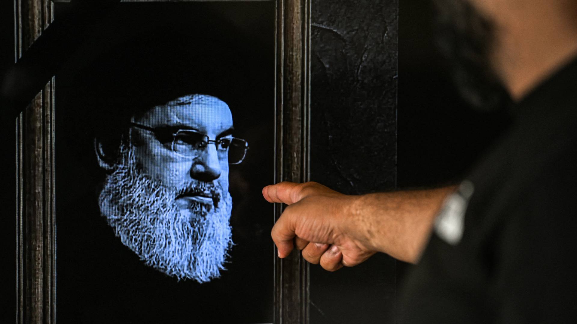 شخص يشير إلى صورة حسن نصرالله