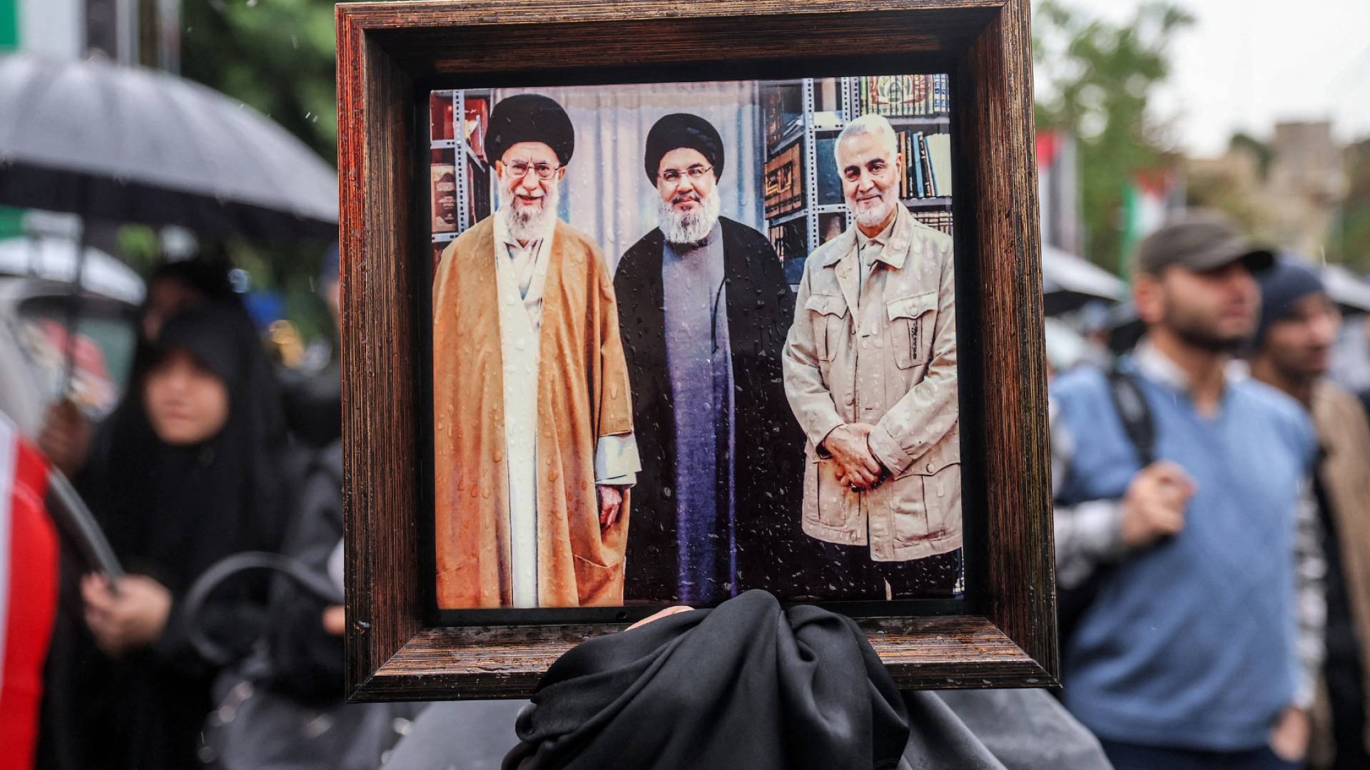 متظاهرة في إيران تحمل صورة تجمع حسن نصرالله وعلي خامنئي