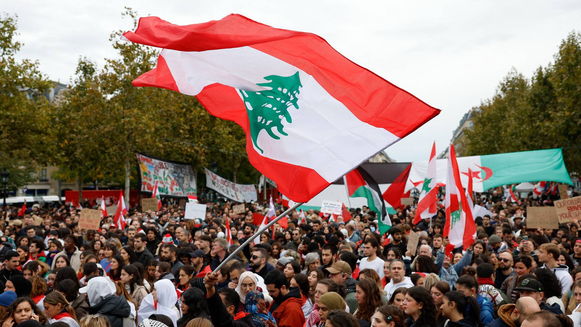 متظاهرون يلوحون بالأعلام اللبنانية والفلسطينية خلال مظاهرة لدعم الشعب اللبناني في باريس