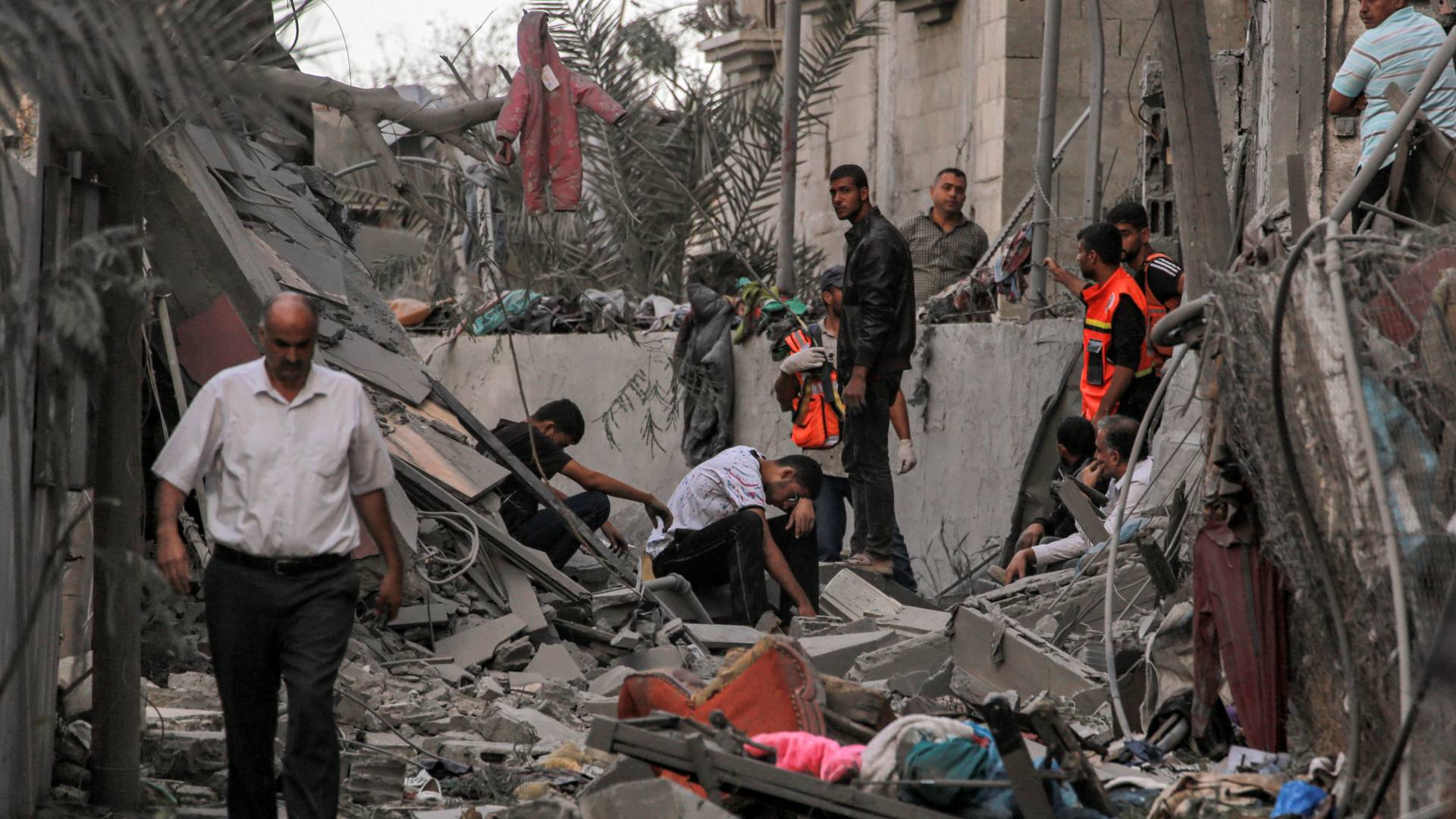 رجال إنقاذ من الدفاع المدني الفلسطيني قفون وسط أنقاض مبنى منهار في خان يونس بجنوبd قطاع غزة