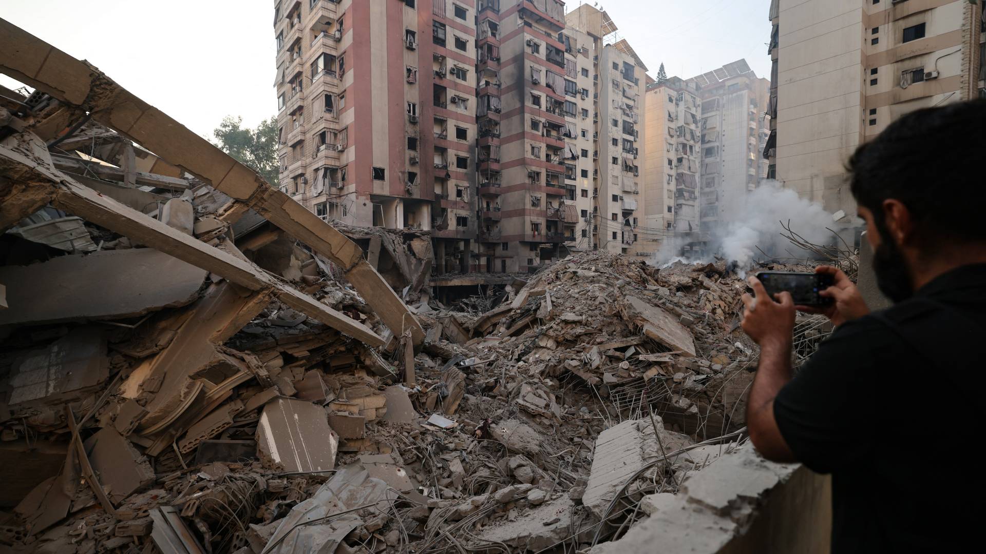 رجل يصور أنقاض مبنى سوته غارة جوية للاحتلال استهدفت الضاحية الجنوبية لبيروت