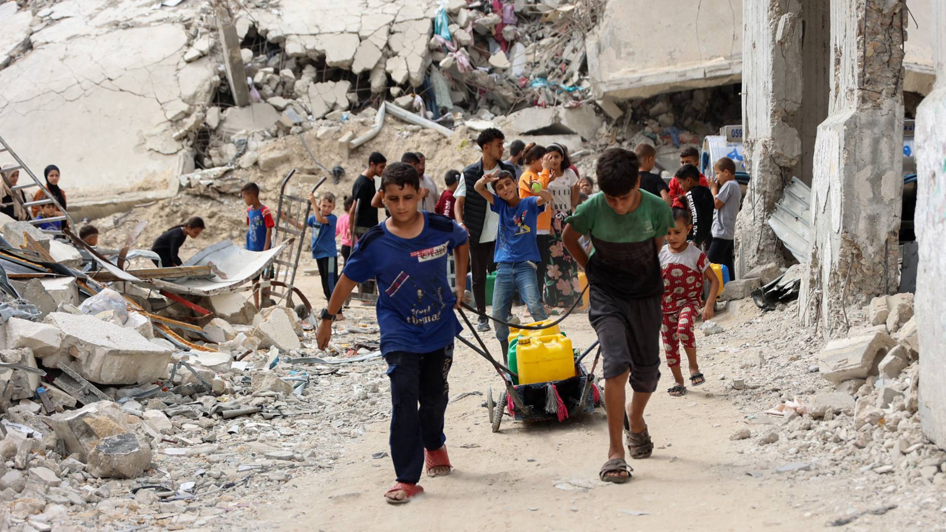 شباب فلسطينيون نازحون يحملون حاويات لنقل المياه من نقطة توزيع في حي الشجاعية بمدينة غزة