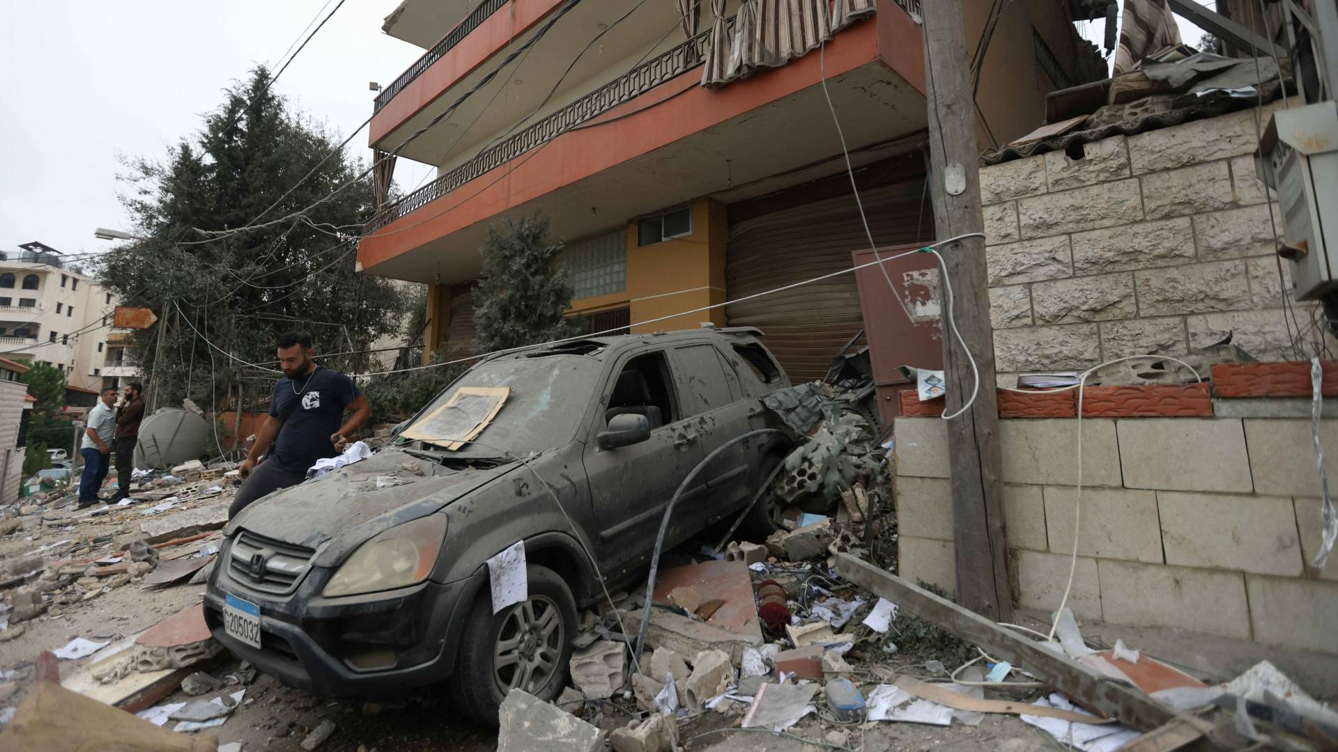 أشخاص يتفقدون الأضرار في اليوم التالي لغارة جوية للاحتلال على مبنى في قرية قماطية بجبل لبنان